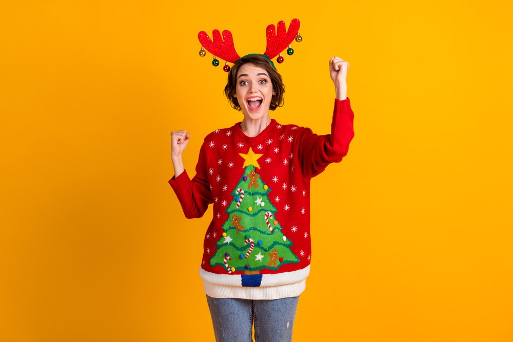 Mujer emocionada usando un suéter con motivos navideños. | Foto: Shutterstock