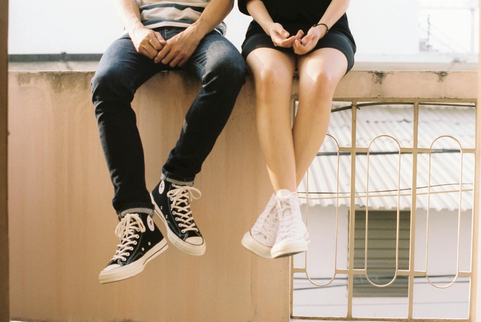 Young couple sitting on a wall wearing converse | Source: Pexels