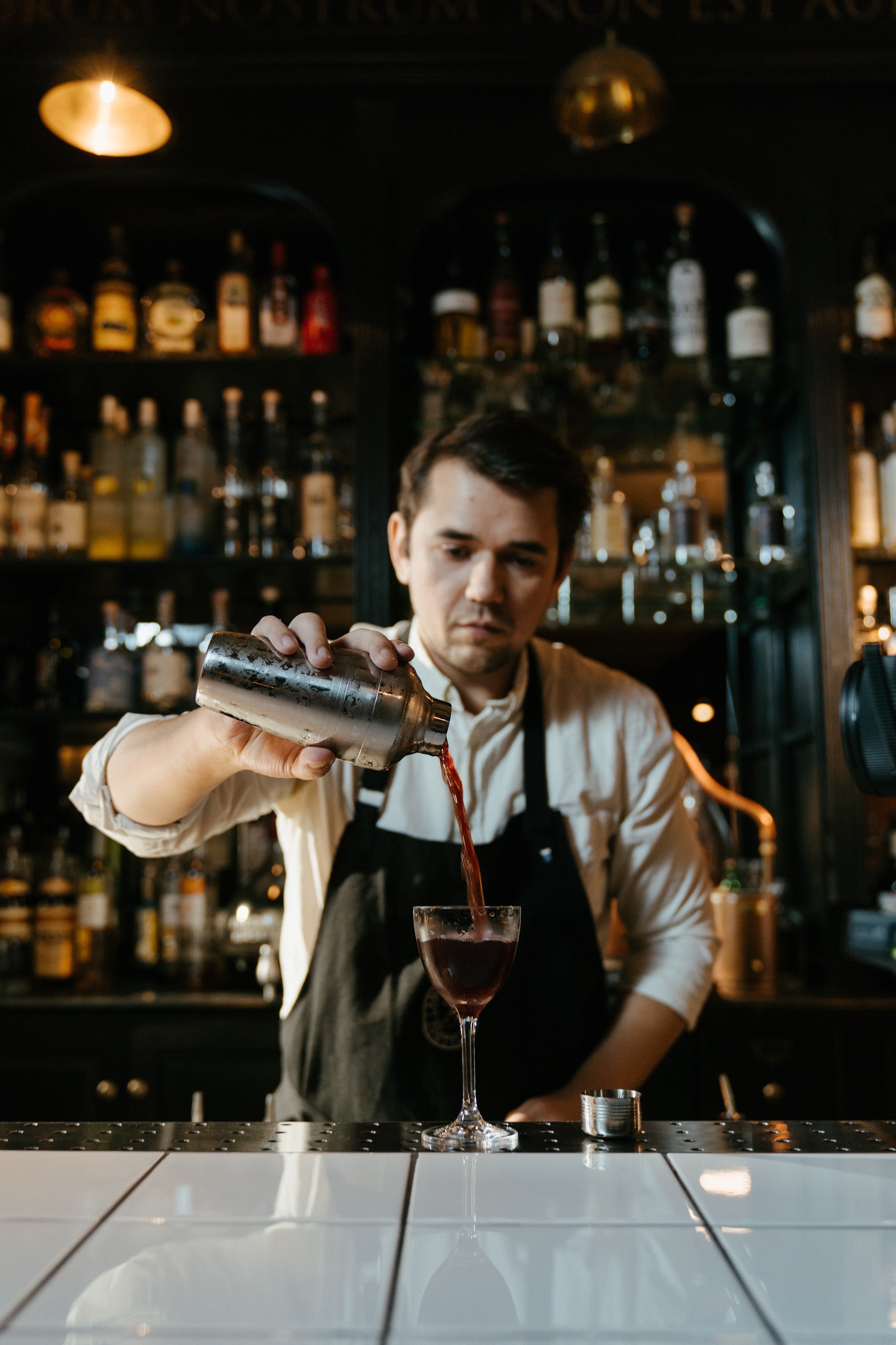 Barkeeper gießt Getränke am Tresen ein. | Quelle: Pexels/ Cottonbro