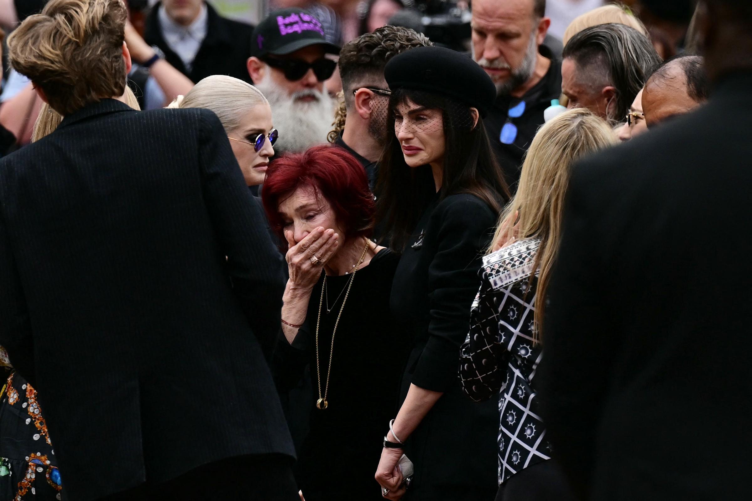 Sharon, Kelly, and Aimee Osbourne react to the tributes left at Black Sabbath Bridge bench during Ozzy's funeral procession in Birmingham on July 30, 2025 | Source: Getty Images