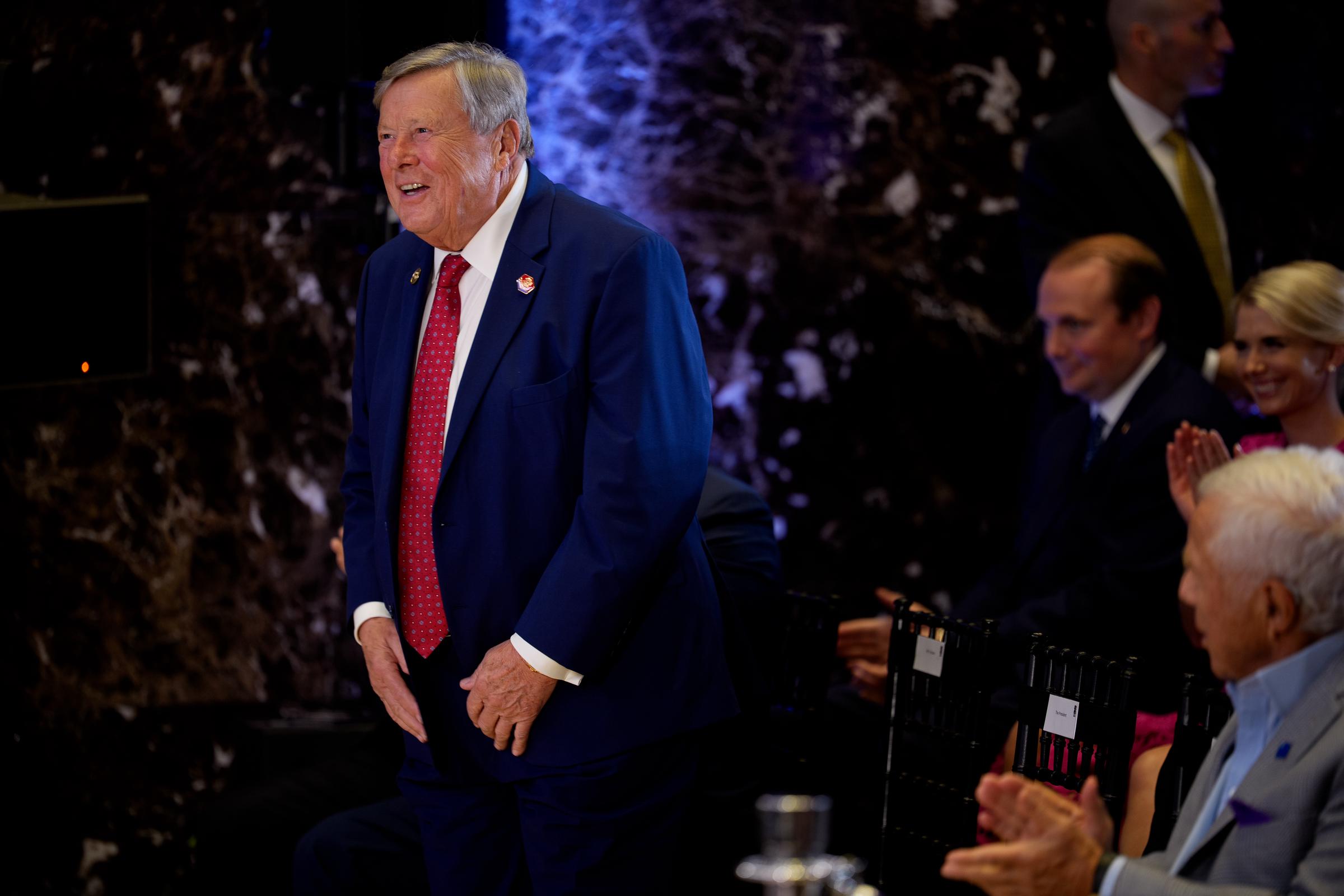 Viktor Knavs stands as President Donald Trump recognizes him during a FIFA reception at Trump Tower ahead of the 2026 FIFA World Cup Final. The moment offered a rare public acknowledgment of Melania Trump's father just two days before he appeared with the family at the championship match. | Source: Getty Images