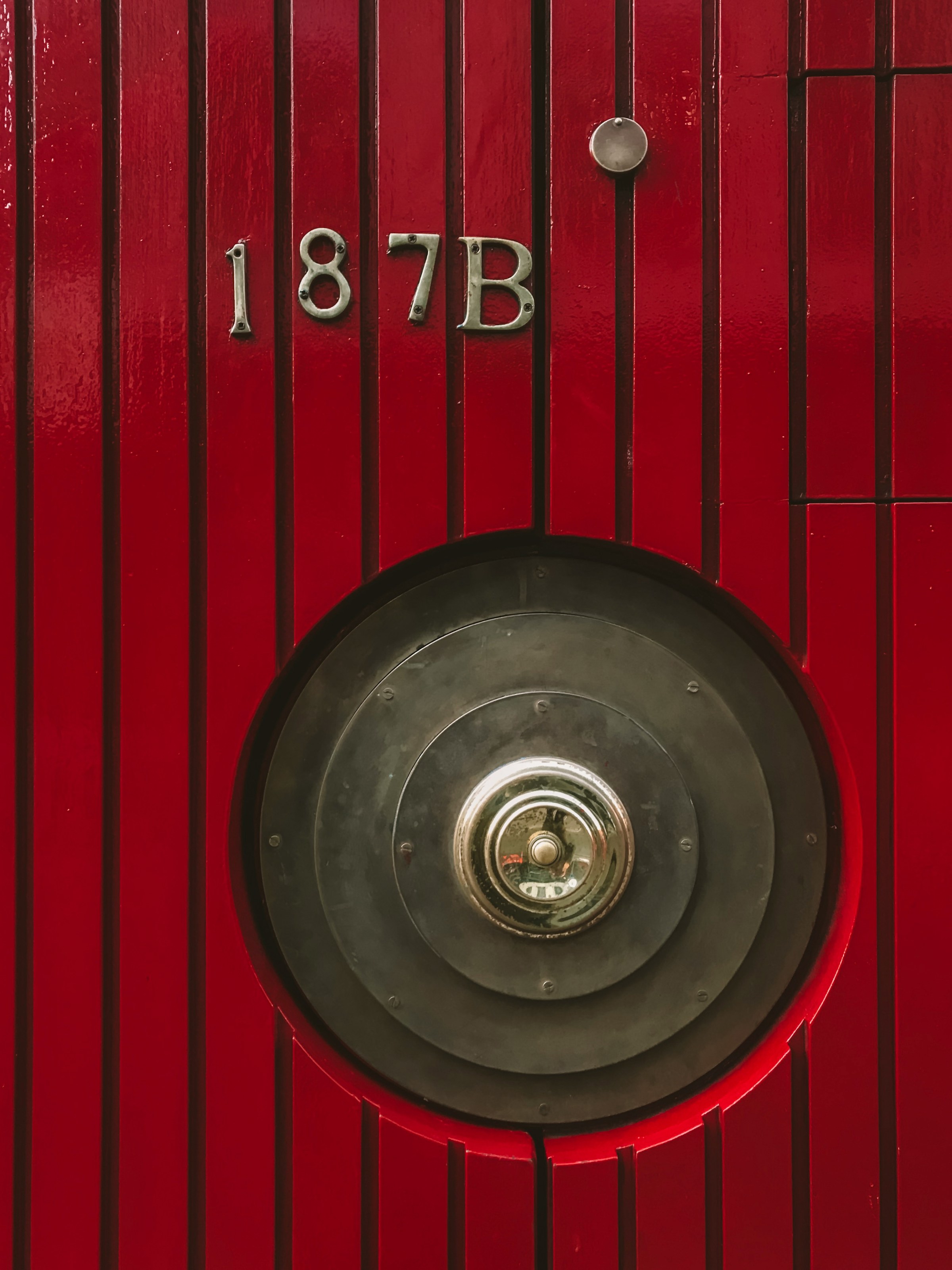 A red door with a metal doorknob | Source: Unsplash