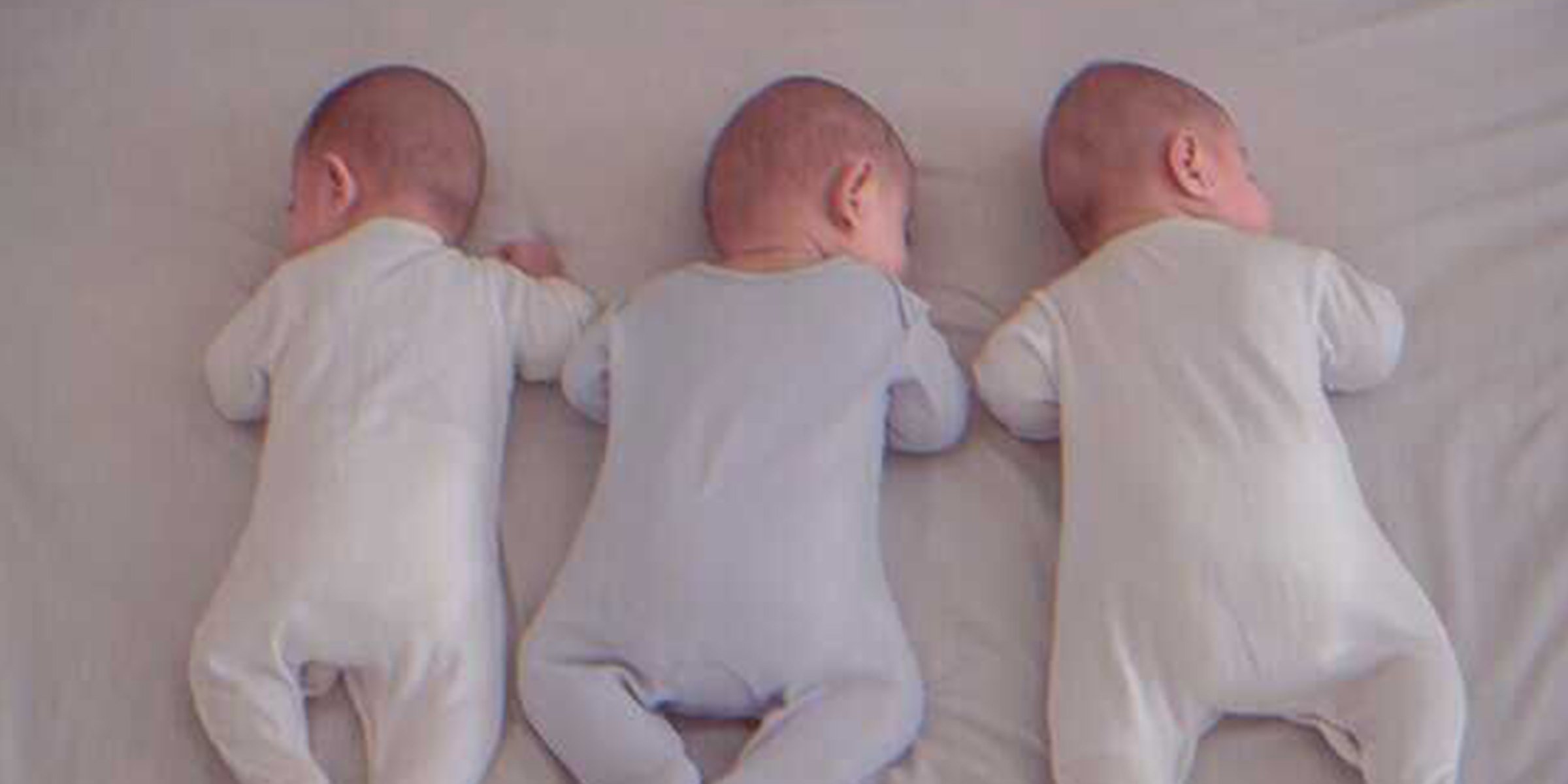 Triplets sleeping on a bed | Source: Shutterstock