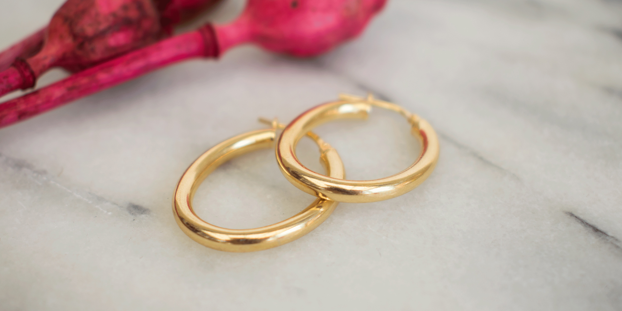 A pair of gold earrings on a marble surface | Source: Shutterstock