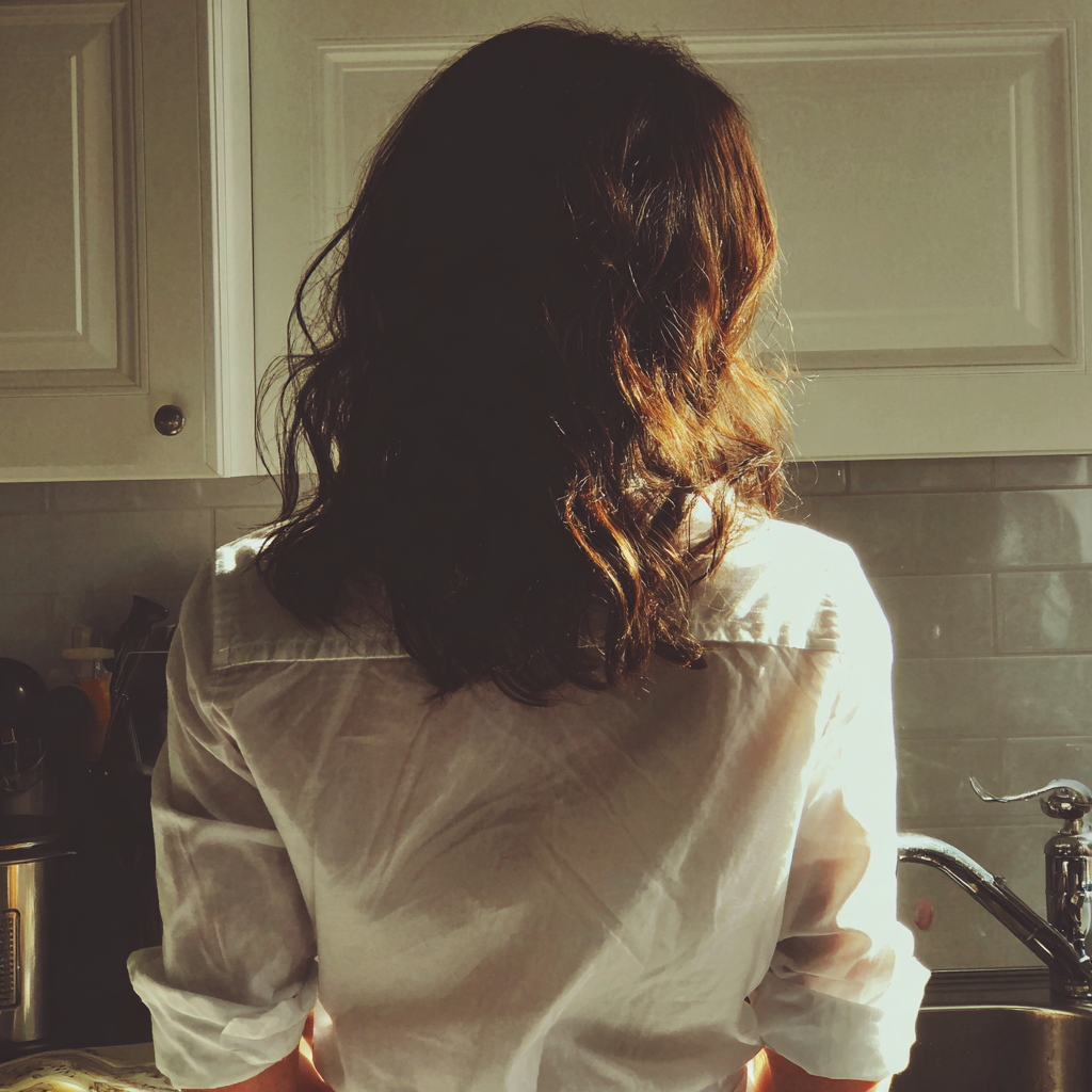 A woman standing at a kitchen sink | Source: Midjourney