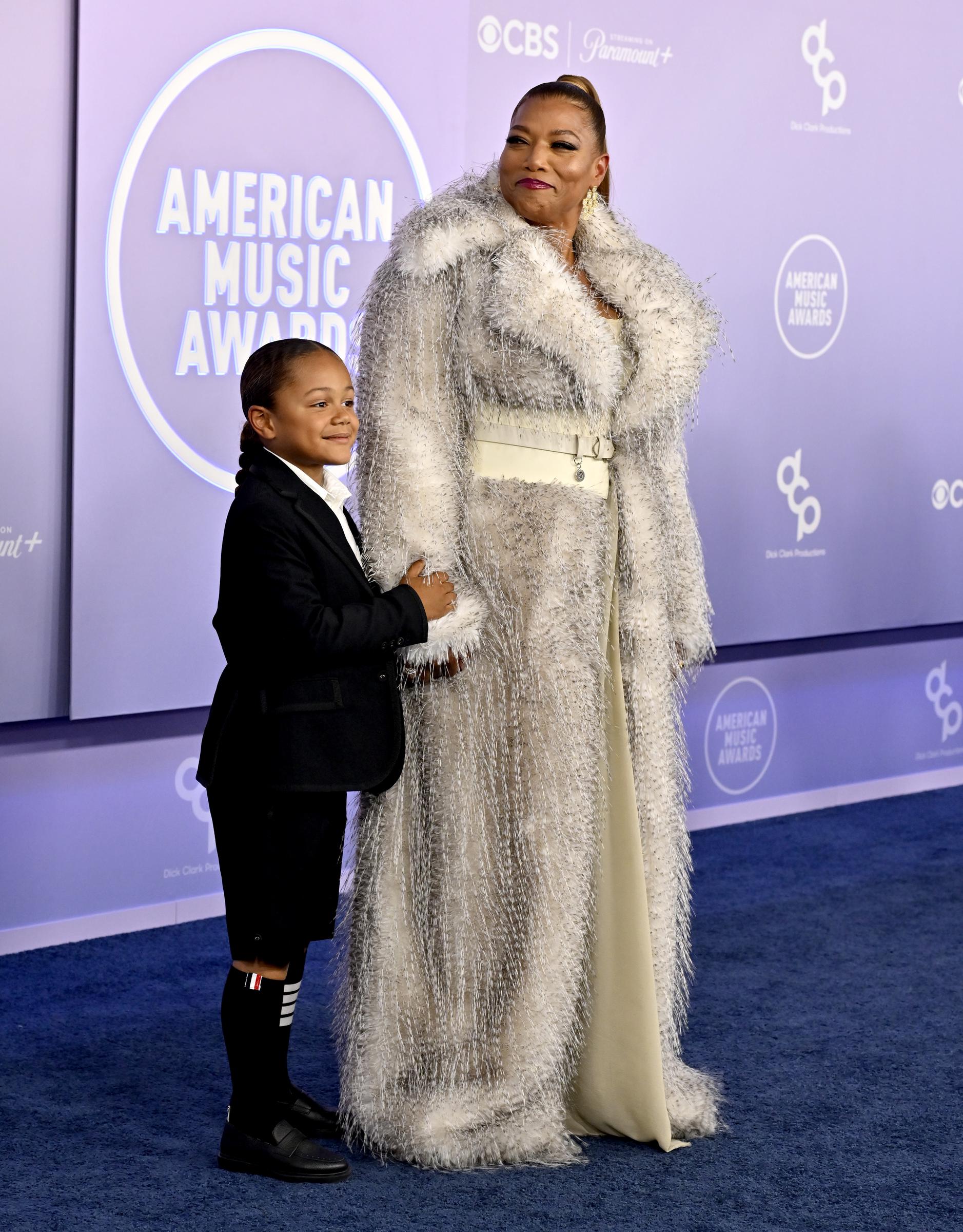 Rebel Nichols Owens stands close beside Queen Latifah while resting a hand against her silver coat during their rare joint appearance at the American Music Awards.