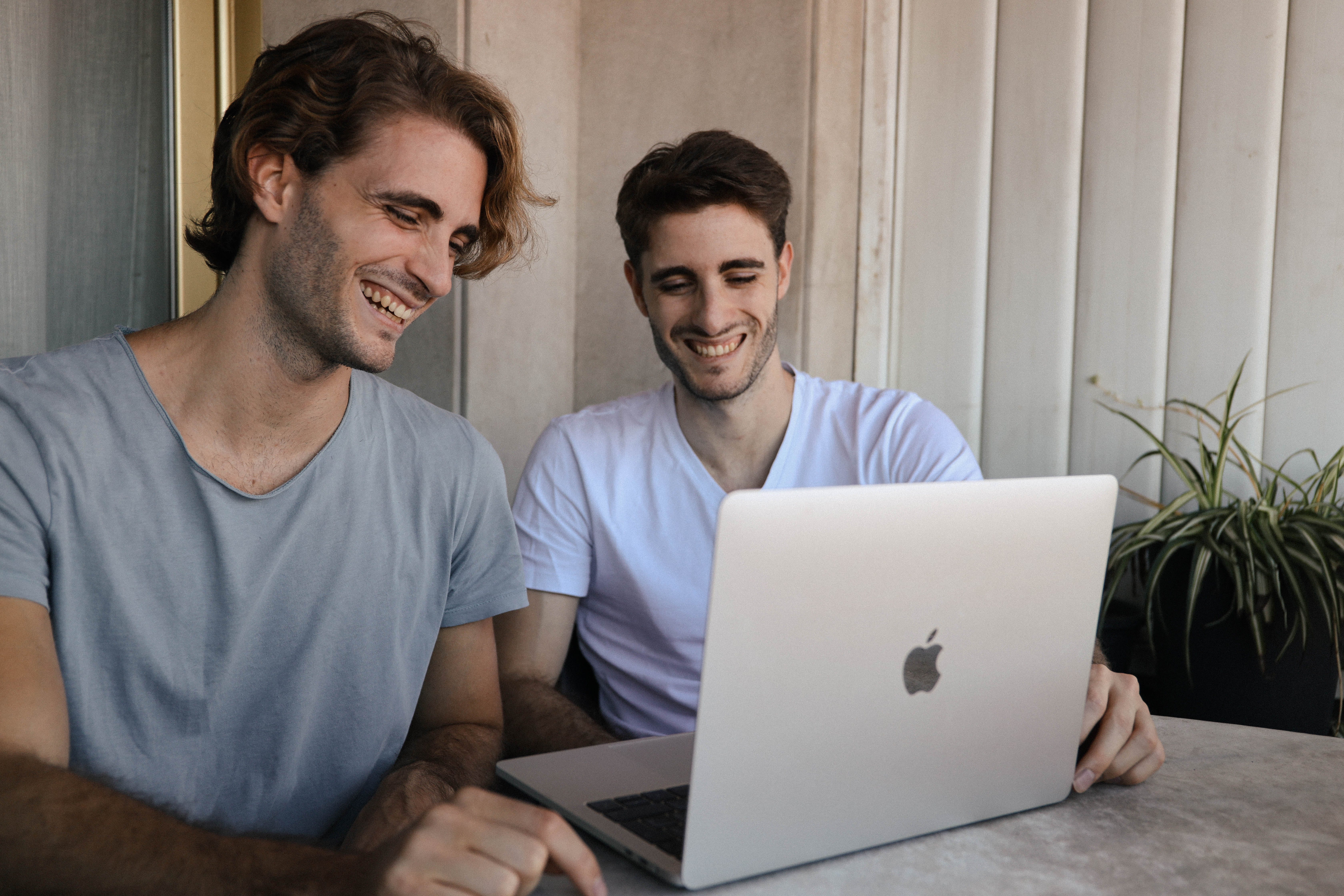 Two young men laughing while using a laptop | Source: Pexels