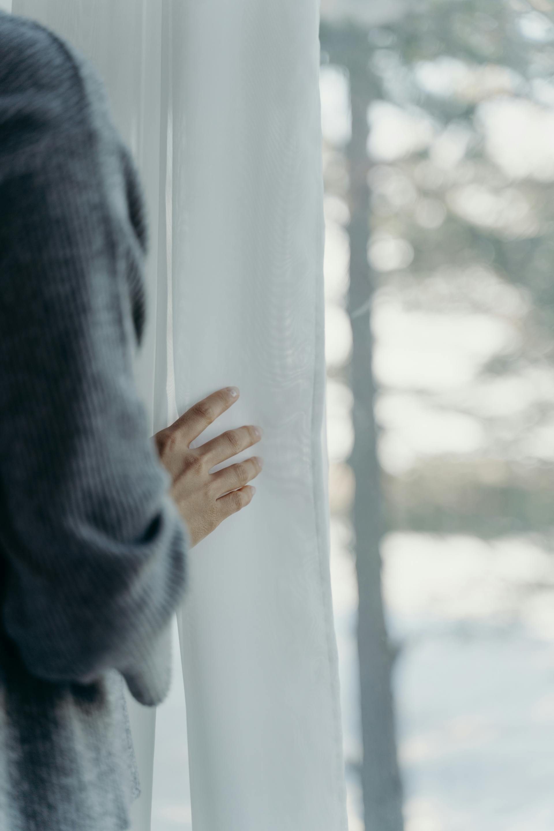 A person standing near a white curtain | Source: Pexels