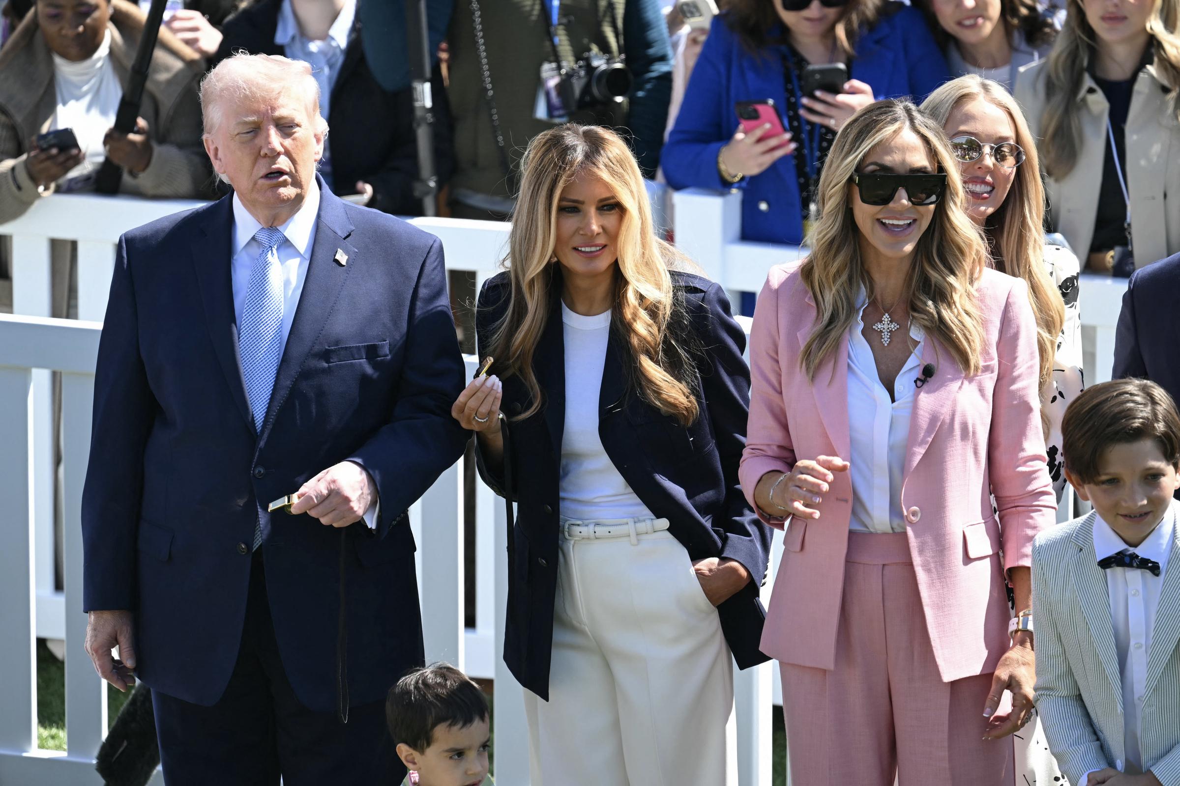 Donald and Melania Trump walk with guests on the South Lawn, joined by attendees, Lara and Tiffany Trump and kids, in pastel outfits and surrounded by families.