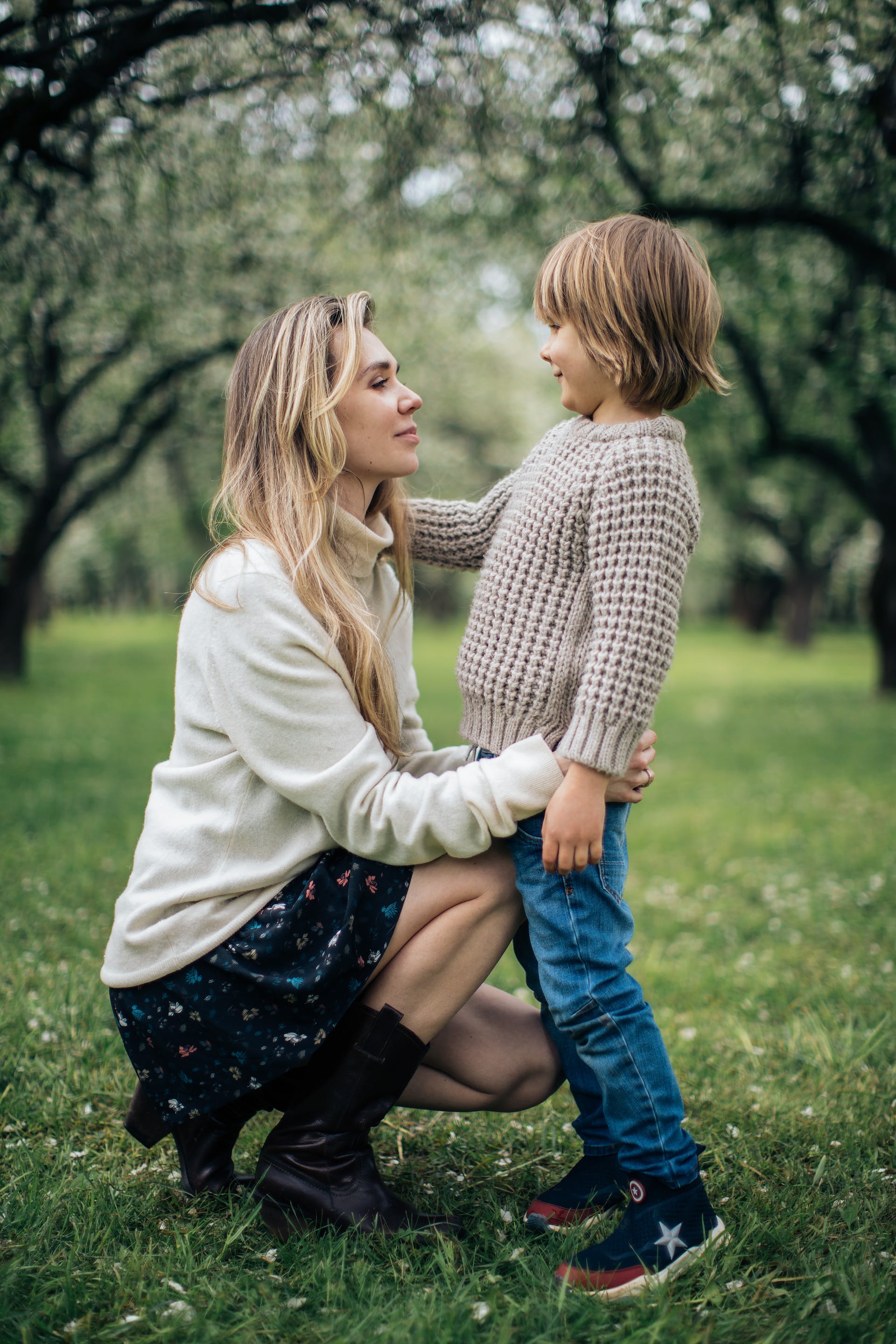 A mother and child standing on a grassy field while looking at each other | Source: Pexels