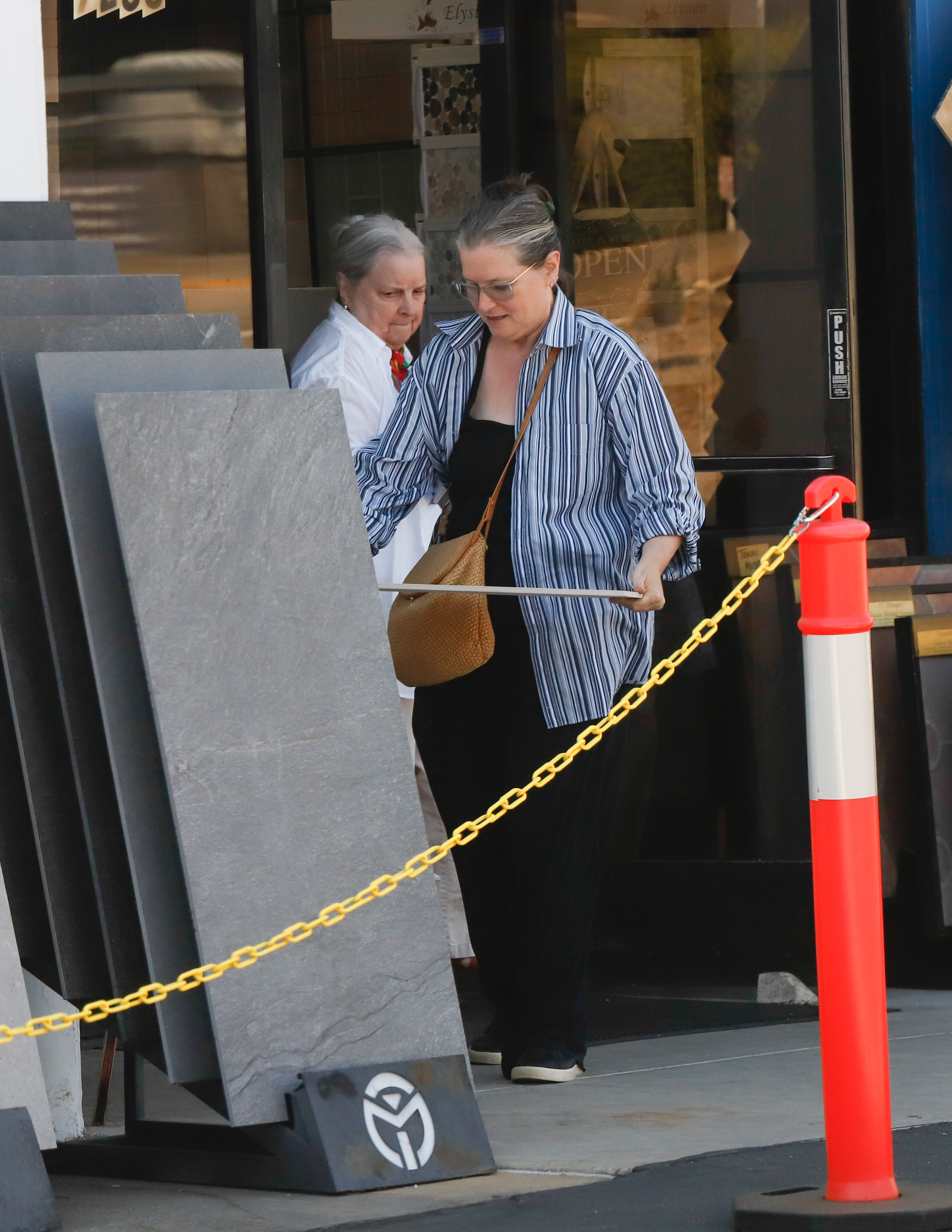 Fonda was later seen exiting a tile and design shop, taking time to examine materials displayed outside the storefront. Wearing loose black trousers and a striped button-down, she maintained a low profile as she quietly navigated the errand on her own.