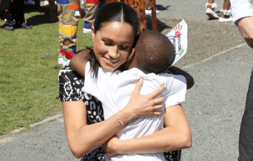 During her tour of Africa with Prince Harry, Meghan Markle hugs a young at the Justice Desk initiative in Nyanga township, on September 23, 2019, in Cape Town, South Africa | Getty Images