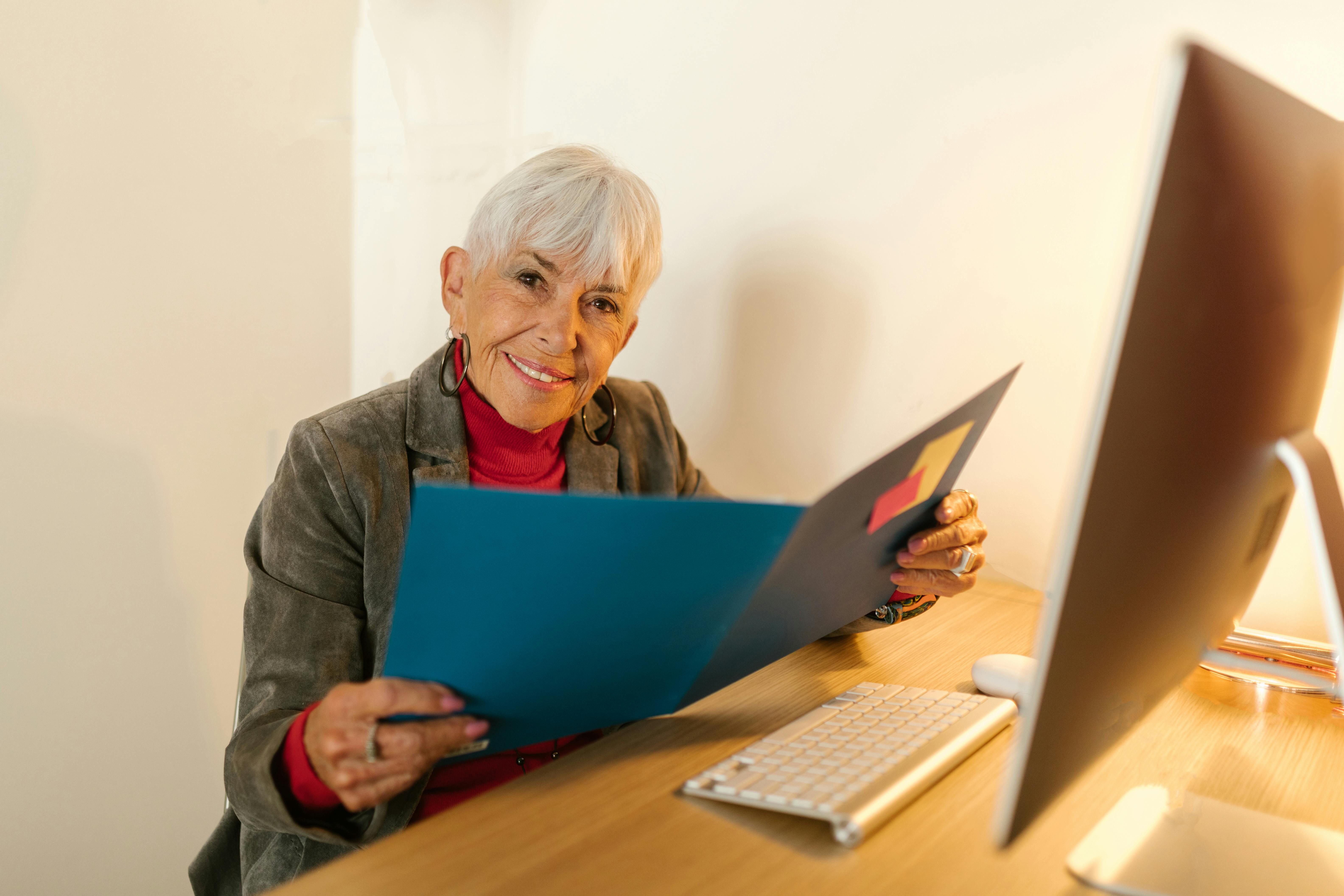 A smiling elderly woman holding a file | Source: Pexels