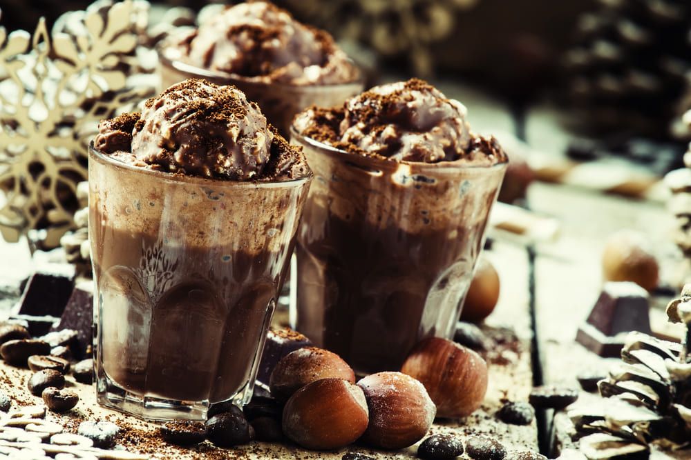 Hot chocolate topped with whipped cream and candy before a Christmas setting. | Source: Shutterstock