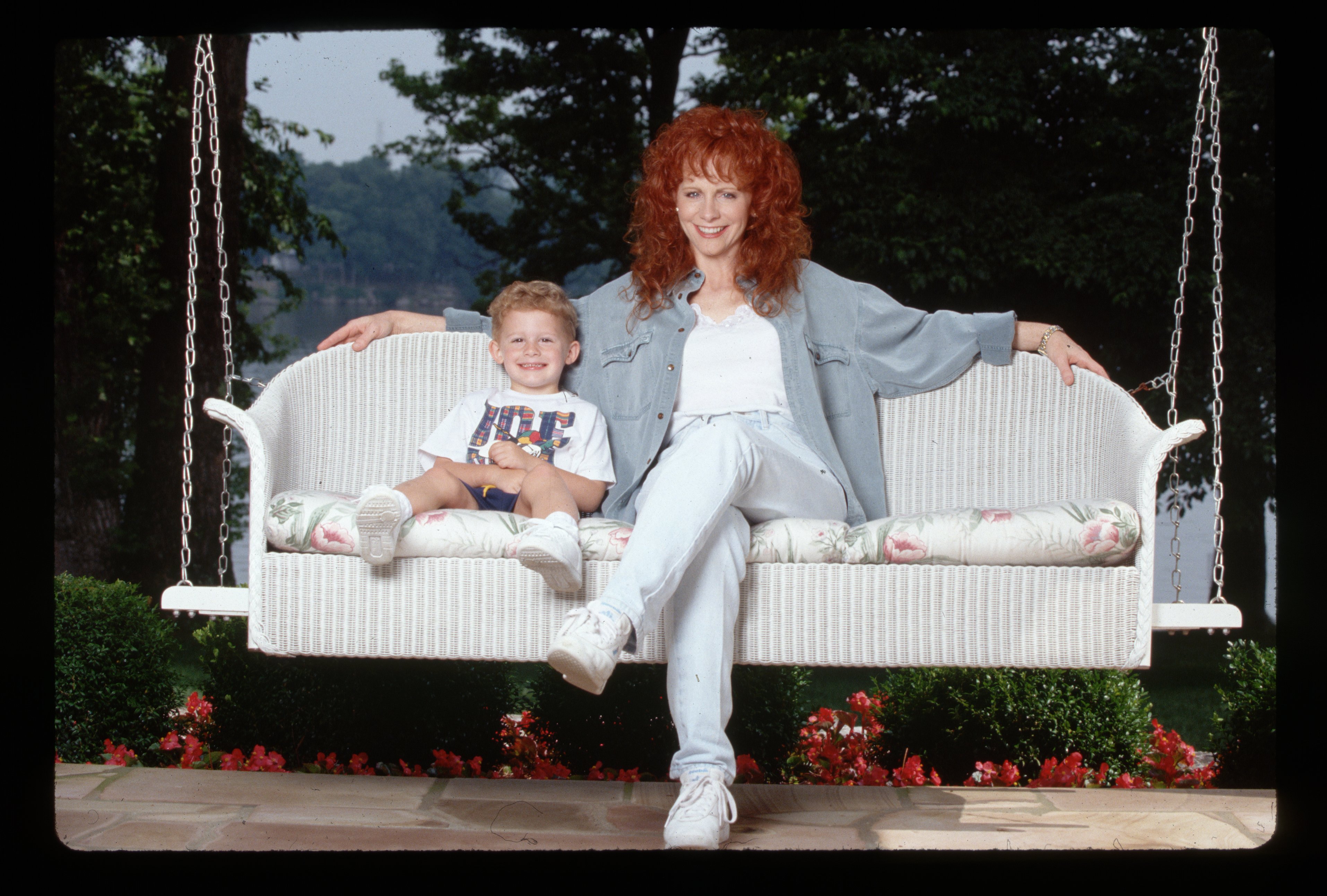 Country singer Reba McEntire and her young son Shelby relax on a porch swing circa 1994 | Source: Getty Images