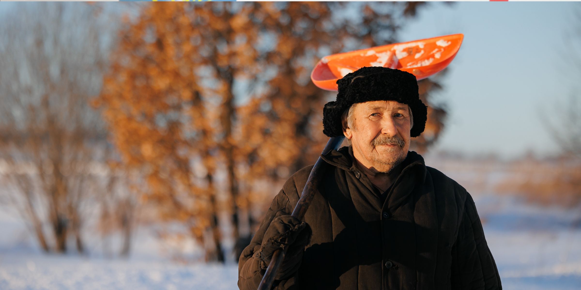 Elderly man carrying a shovel in the winter | Source: Shutterstock