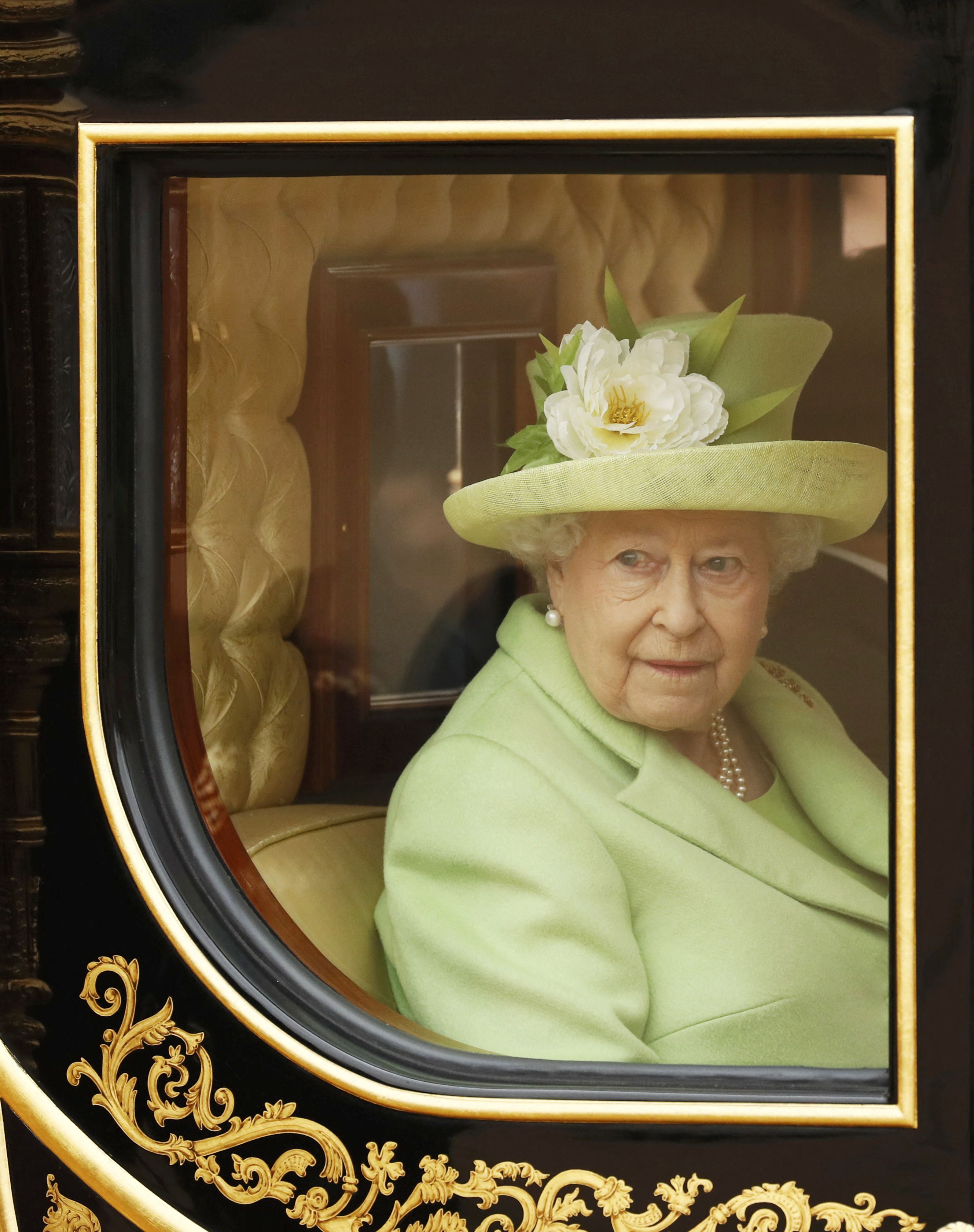 Looking out from her carriage, Queen Elizabeth II appears thoughtful. A burst blood vessel in her right eye is visible, softening her normally unshakable public demeanor during the state visit.