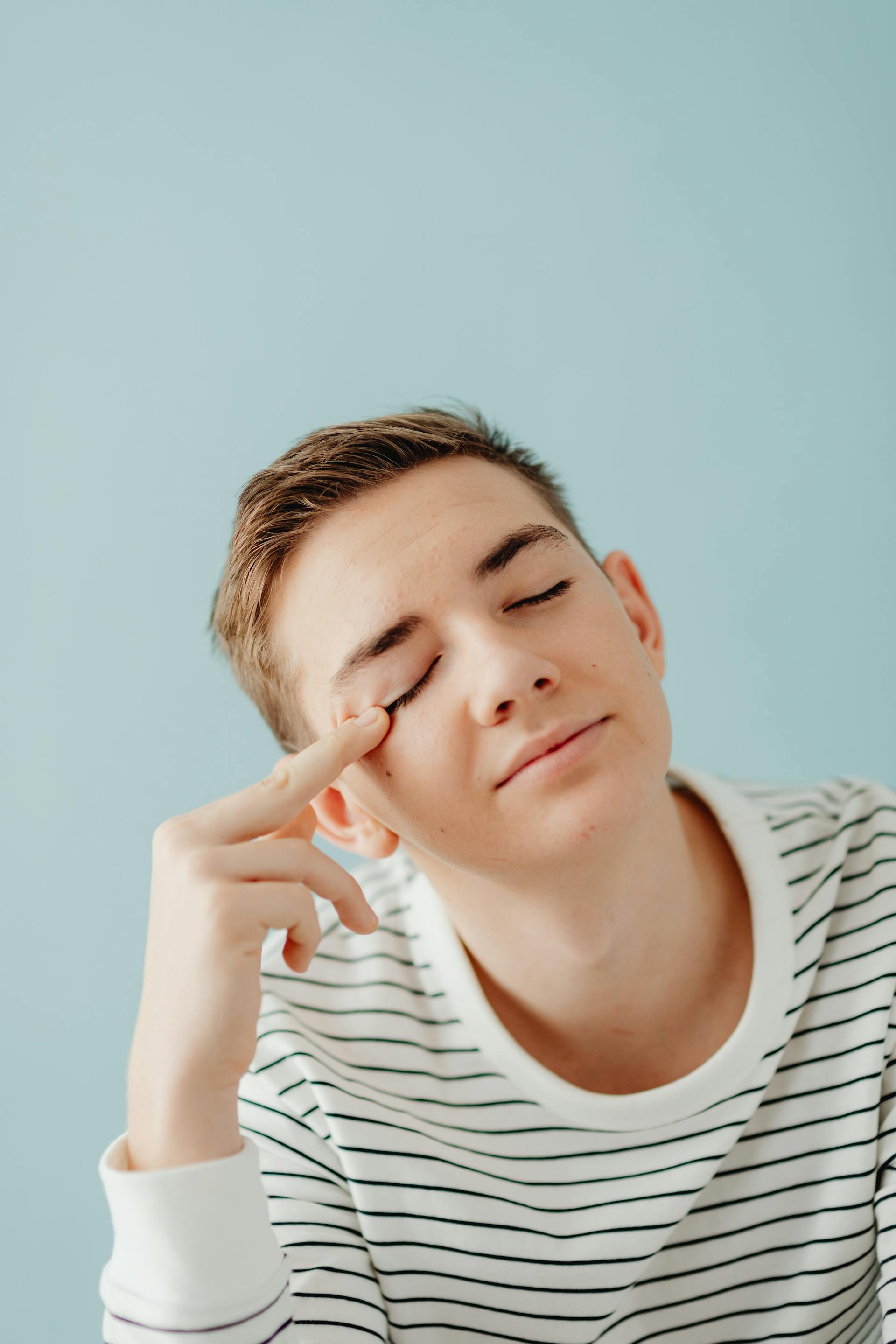 A smiling teenage boy sitting with his eyes closed | Source: Pexels