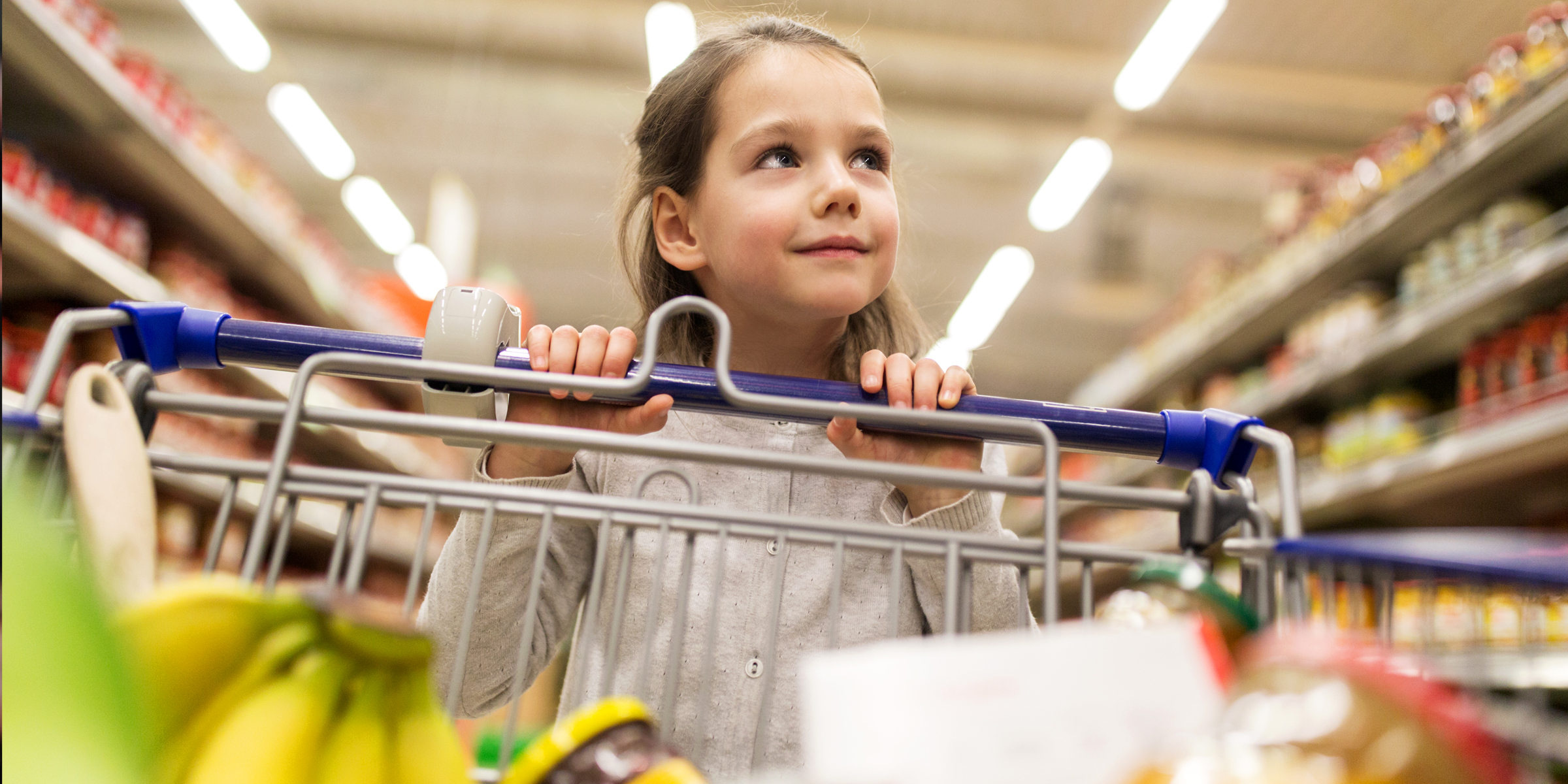 A little girl pushing a shopping cart | Source: Shutterstock
