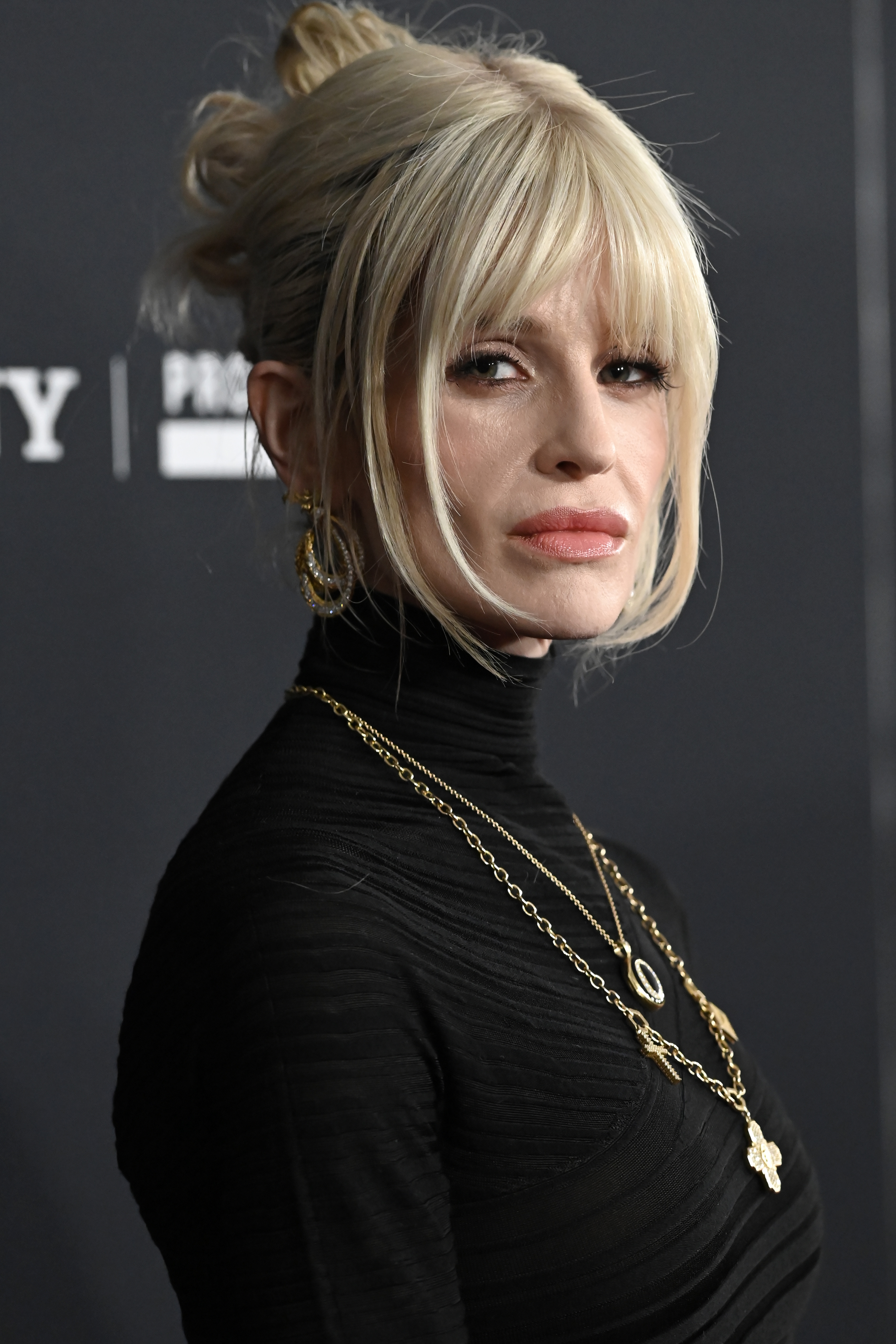Kelly Osbourne is seen in a close-up moment at the 68th Grammy Awards pre-Grammy gala at The Beverly Hilton on January 31, 2026. With her blonde hair styled in an updo and soft fringe framing her face, Kelly appears composed as she moves along the step-and-repeat during the evening honouring music executives Avery Lipman and Monte Lipman.
