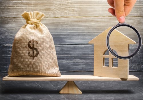 A scaled money bag and wooden house. | Source: Shutterstock.
