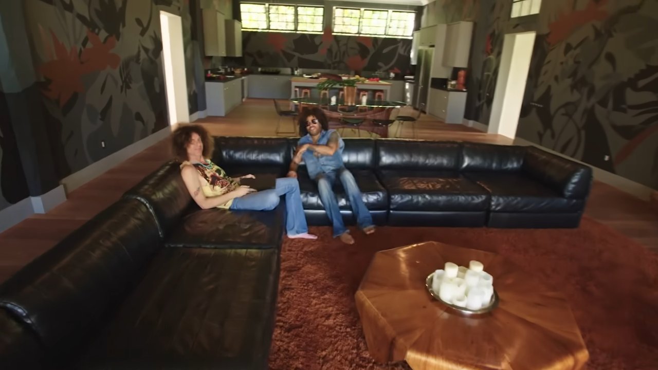 Lenny hangs out with his longtime guitarist, Craig Ross, on an enormous black leather sectional sofa inside the compound's guest quarters. | Source: YouTube/@Archdigest