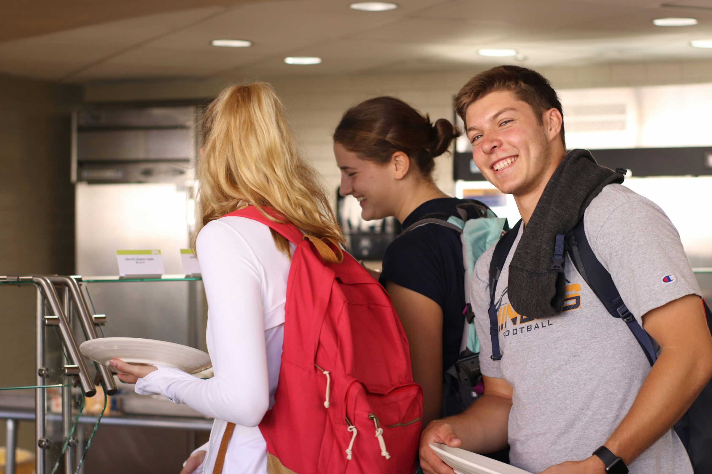 College students holding plates in a cafeteria | Source: Unsplash