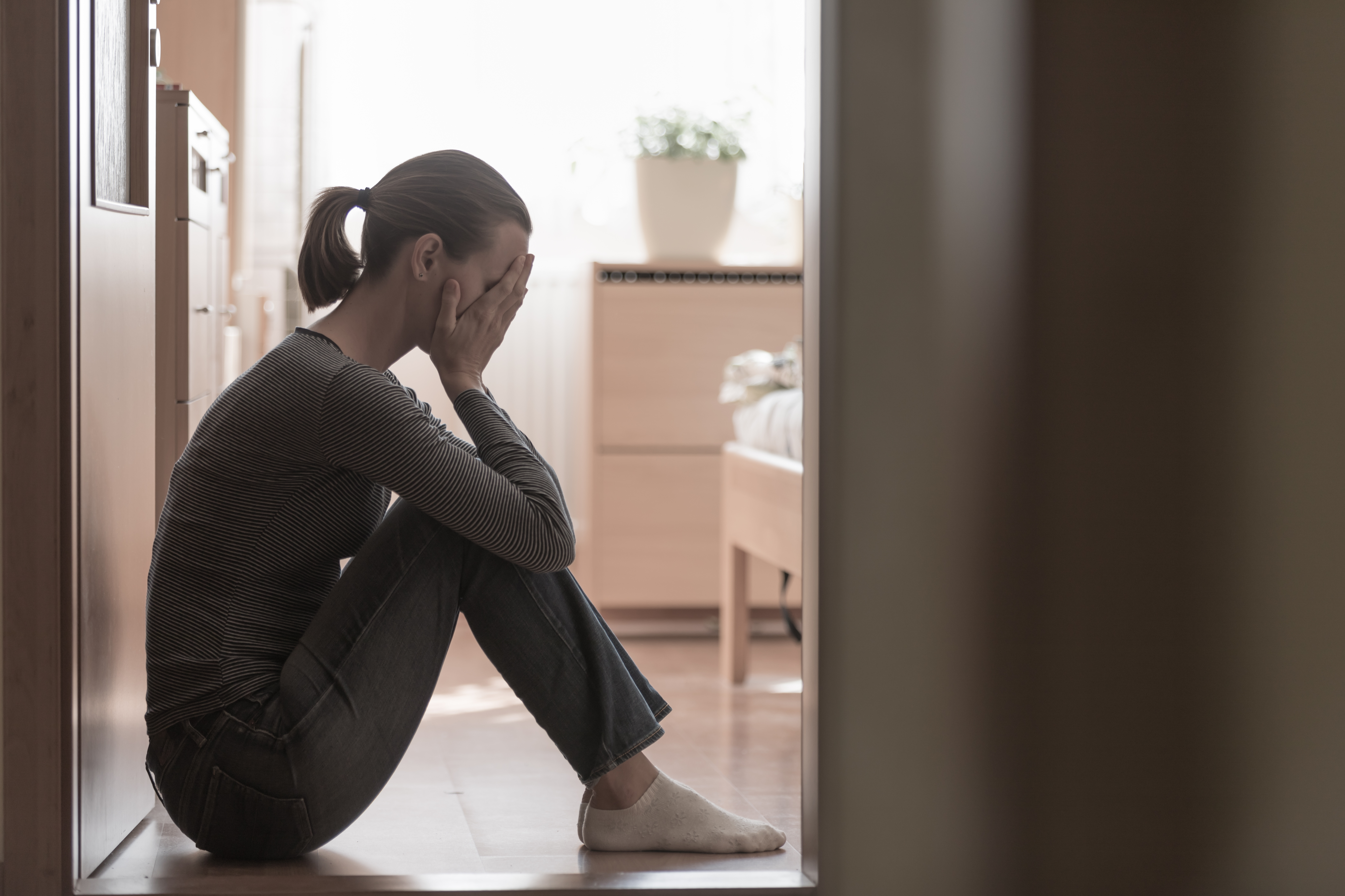 A woman sitting on the floor with her hands covering her face | Source: Shutterstock