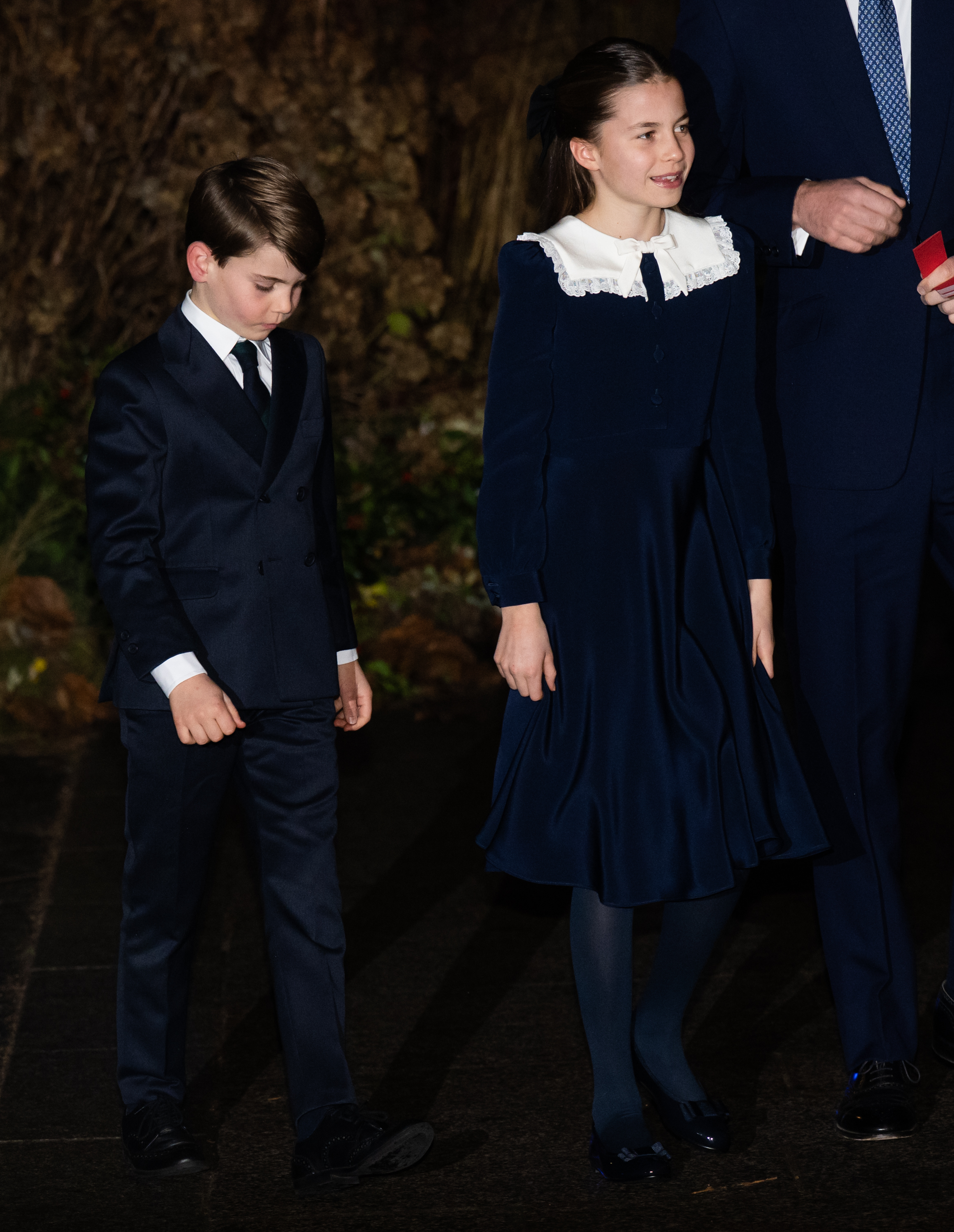 Prince Louis and Princess Charlotte stood side by side in matching navy ensembles, their polished looks and composed presence a subtle reflection of how much they've matured. The young princess's white lace collar and bow added a touch of vintage charm, while the little prince kept close with a shy, downcast gaze.