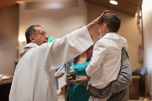Priest pictured anointing a boy in church | Photo: Getty Images