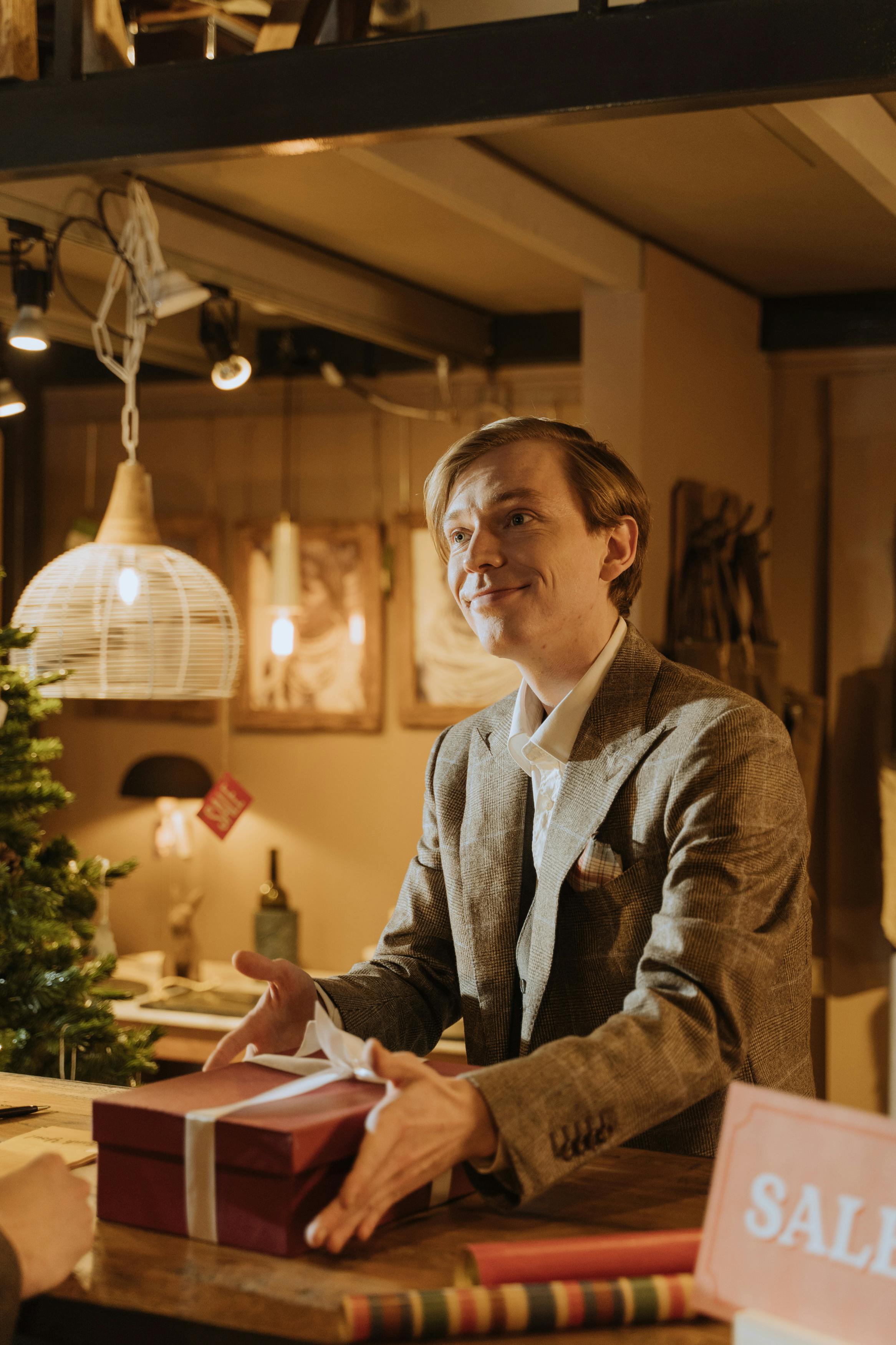 A man in suit smiling at someone while a gift rests on his counter | Source: Pexels