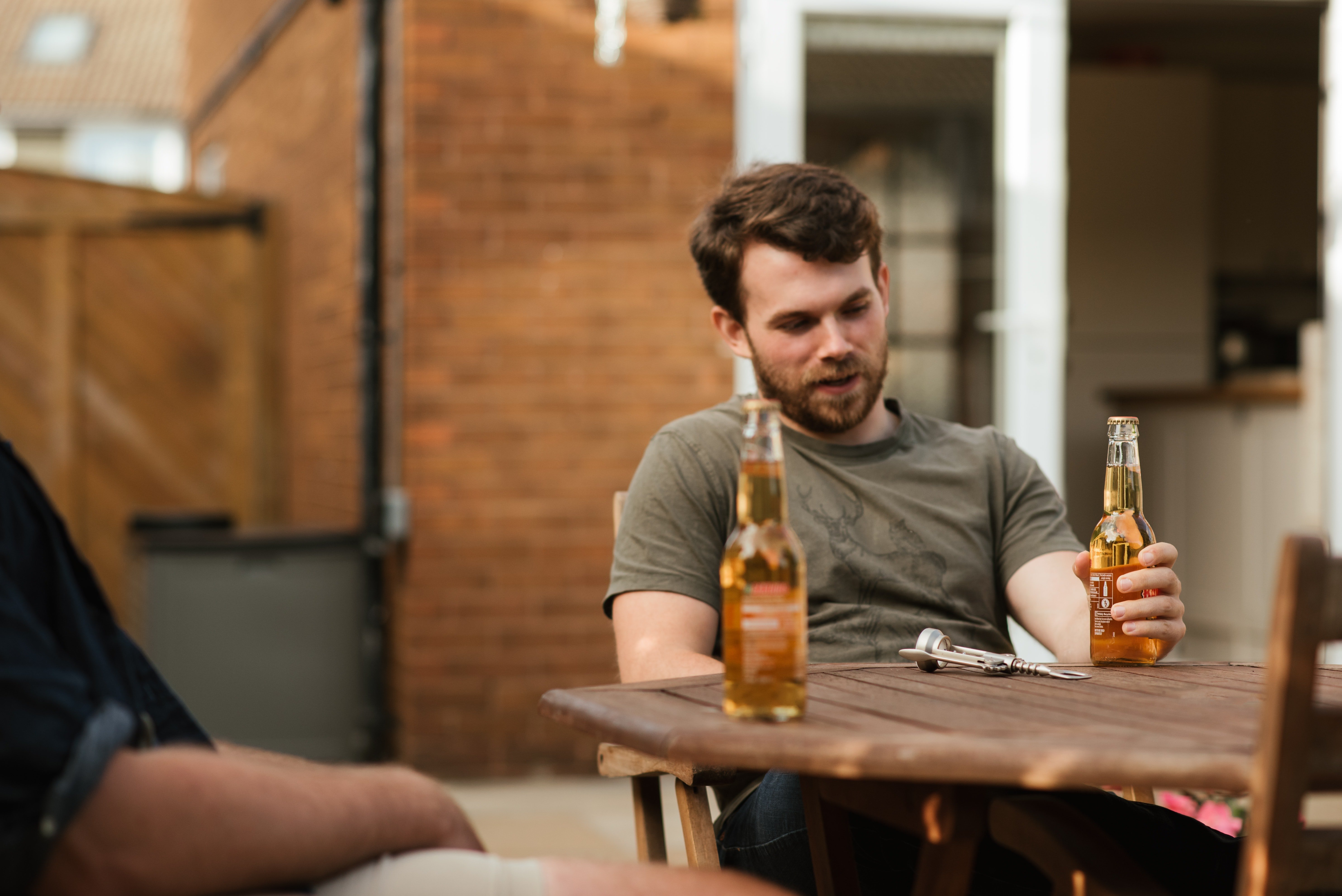 Hombre sentado en el patio con unos amigos compartiendo unas bebidas. | Foto: Pexels