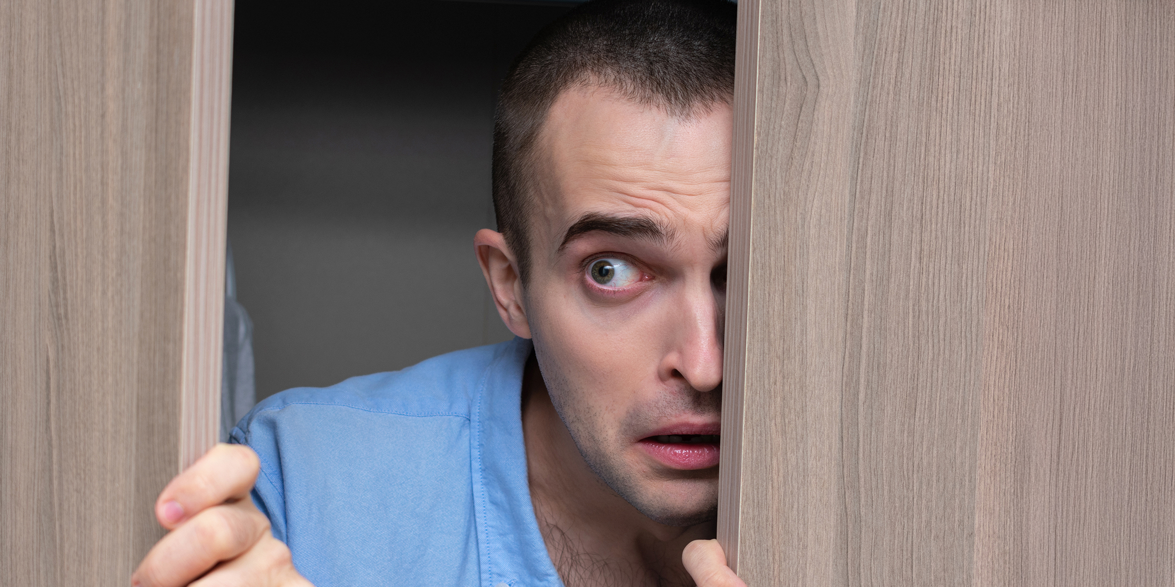 A man peeking through a door | Source: Shutterstock