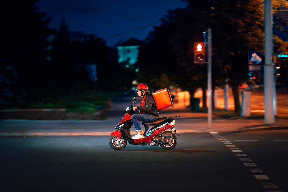 Joven trasladándose en una motocicleta para hacer la entrega de un pedido. | Foto: Shutterstock