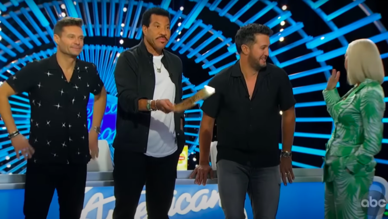 Katy Perry turning around to cry as Luke Bryan looks at her, Ryan Seacrest looks at Doug Kiker, and Lionel Richie holds out Doug's golden ticket. | Source: YouTube/Talent Recap