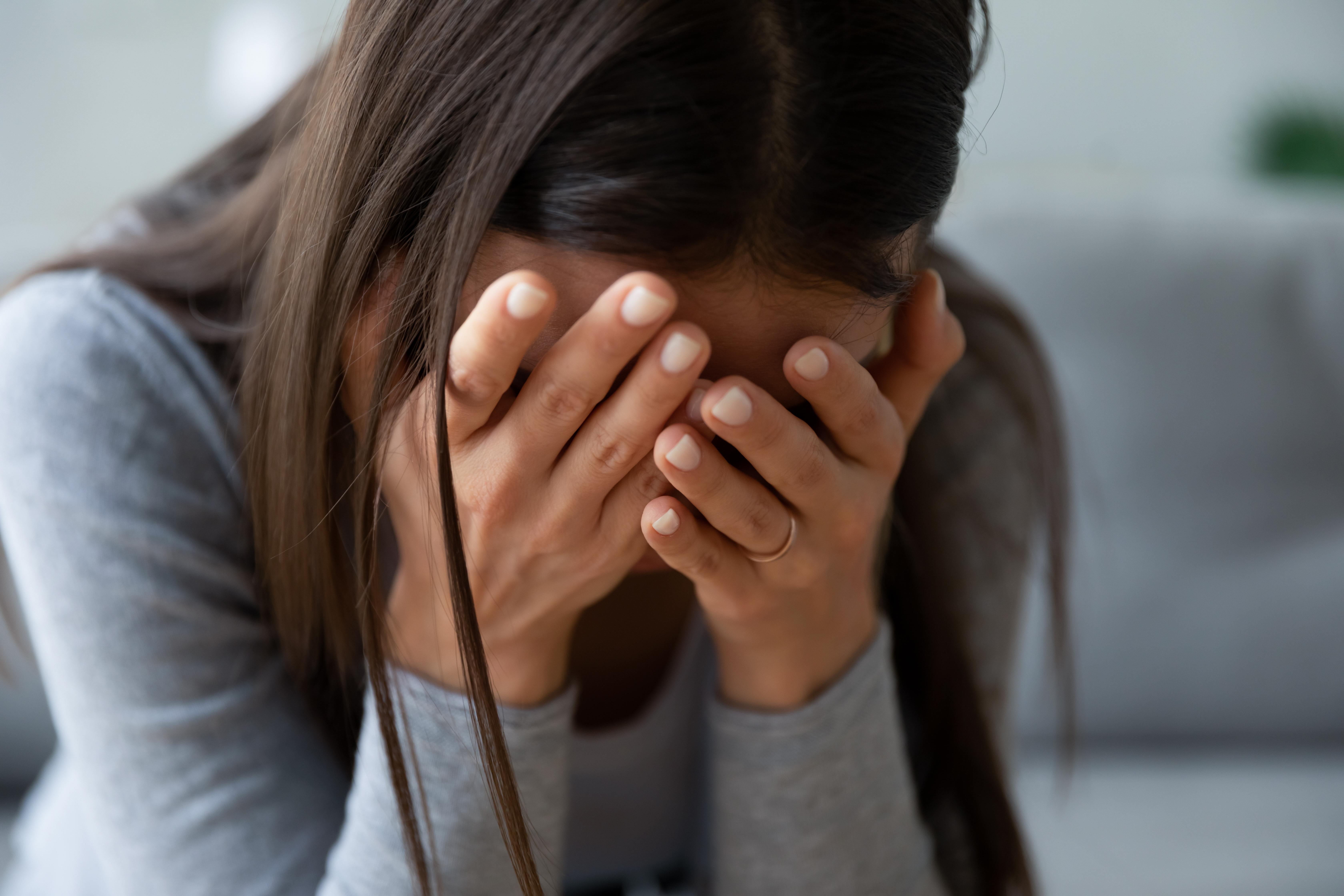 A depressed woman hiding her face with her hands | Source: Shutterstock