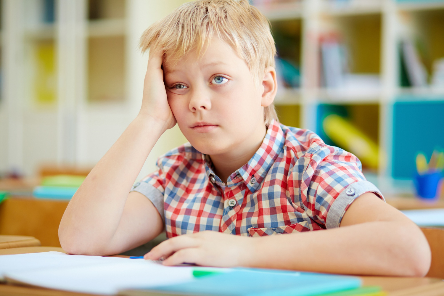 A sad boy seated at a desk | Source: Freepik