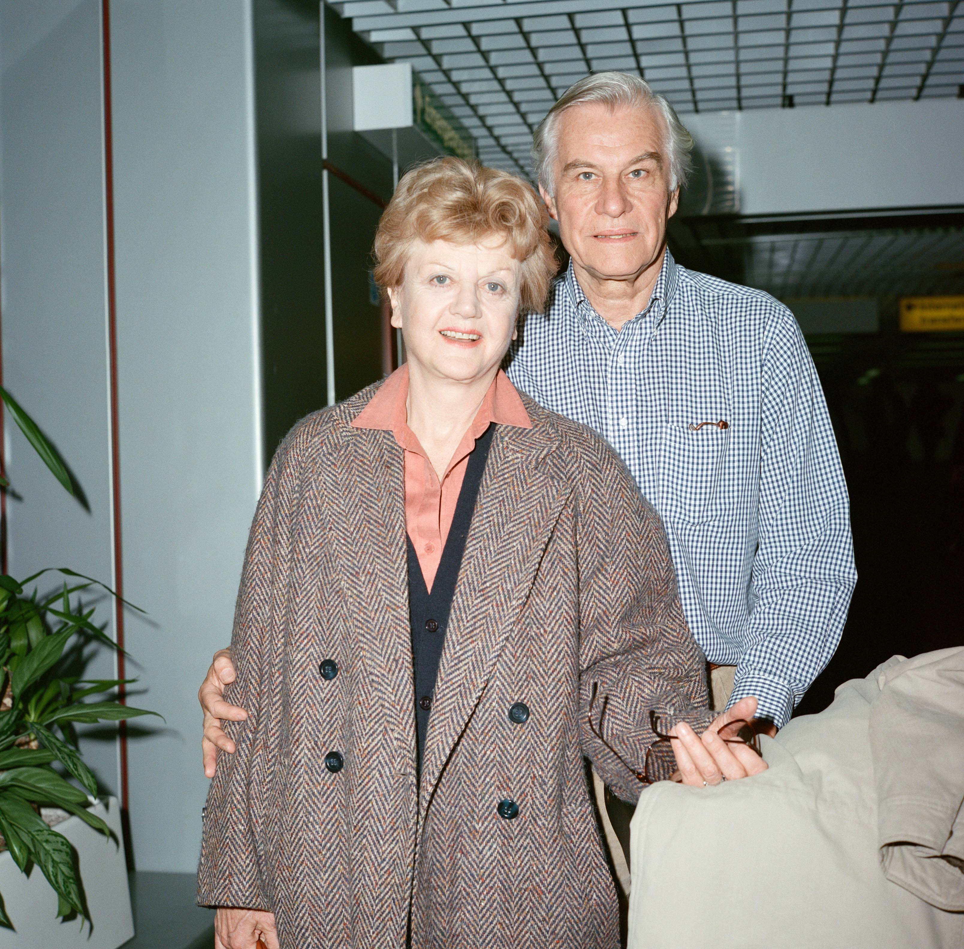 Angela Lansbury and Peter Shaw pose for a photo at the London Airport on March 13, 1990 | Source: Getty Images