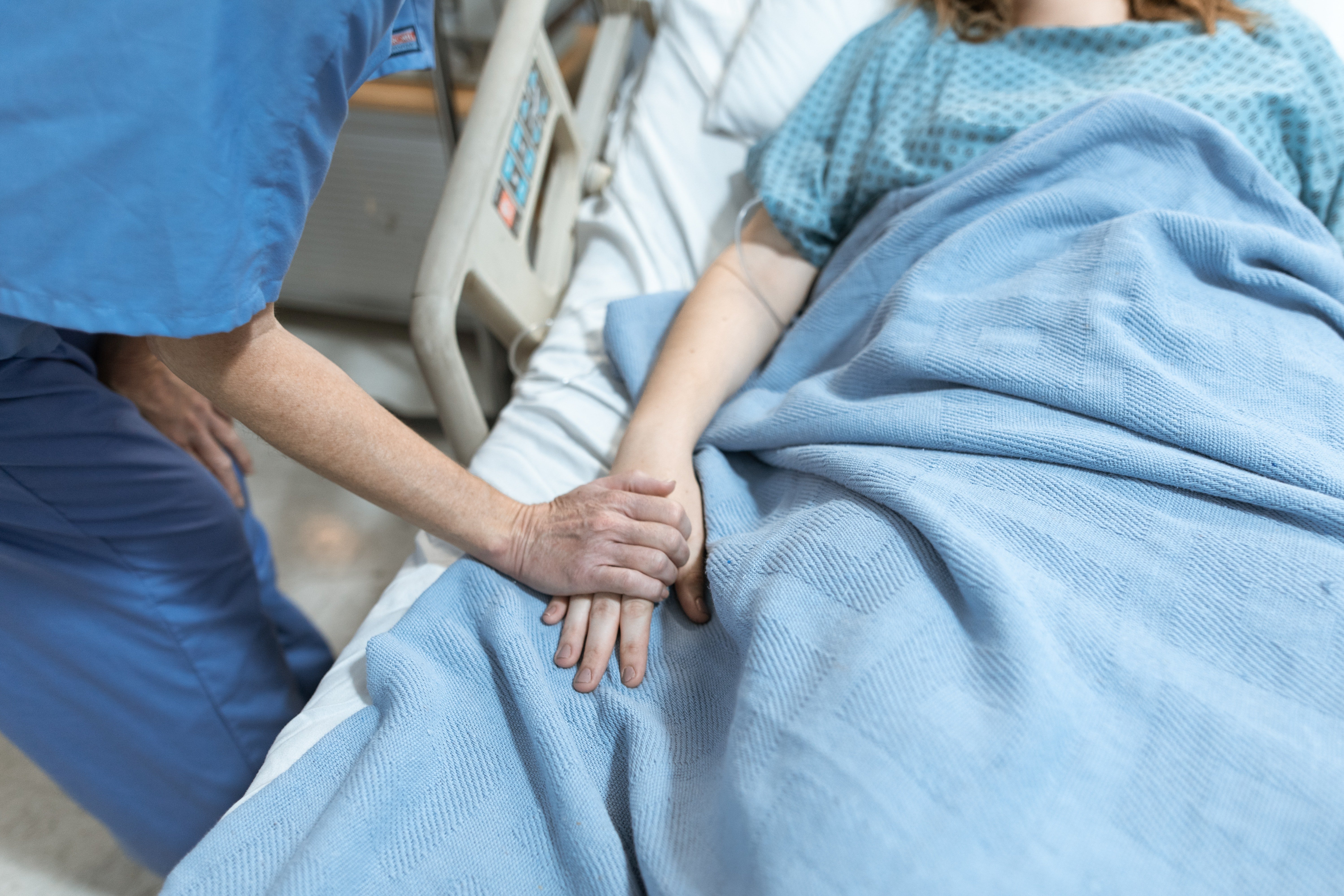 Una mujer recostada en una cama de hospital con una enfermera a su lado. | Foto: Pexels