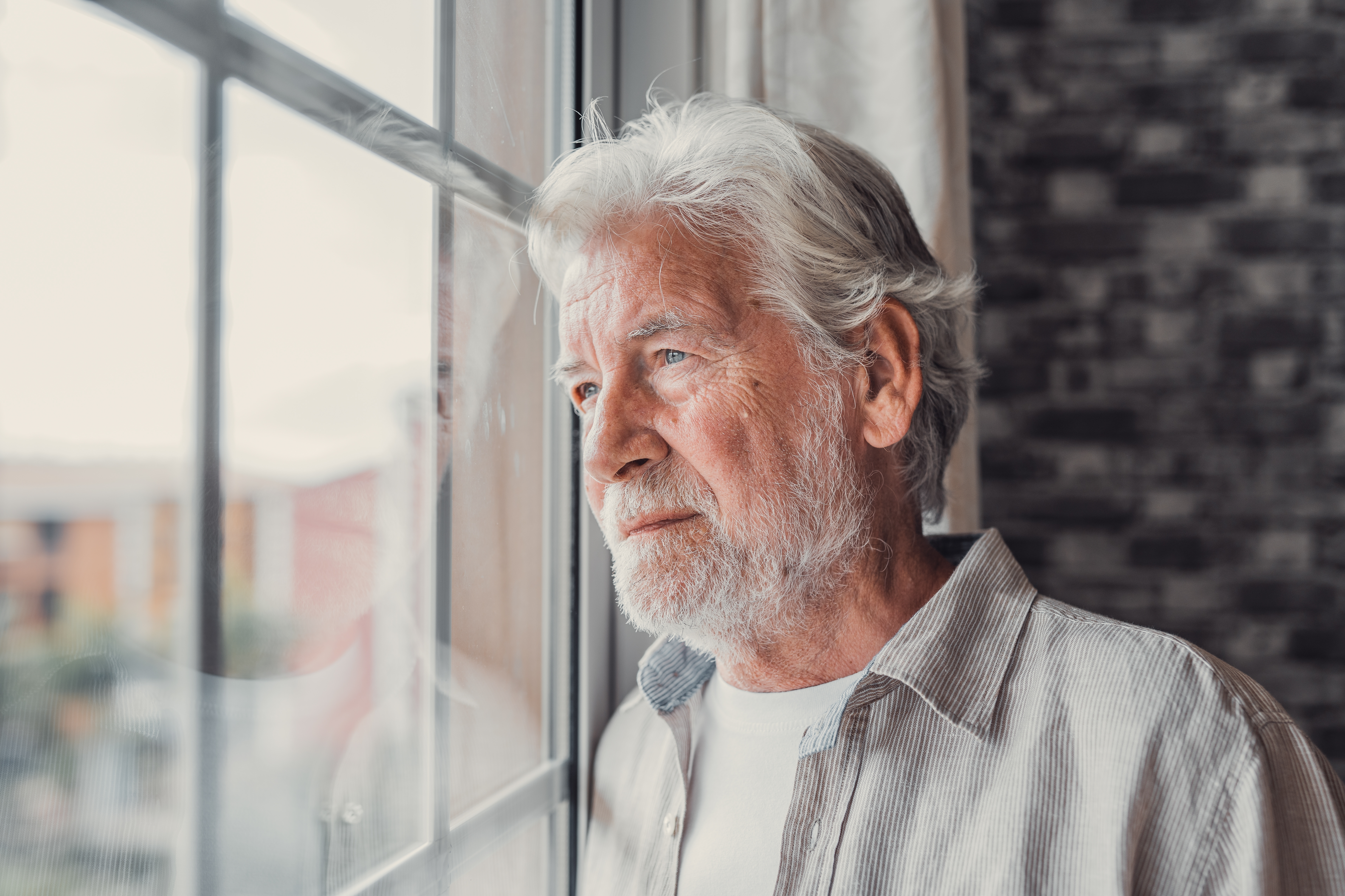 A pensive senior man looking out of the window | Source: Shutterstock