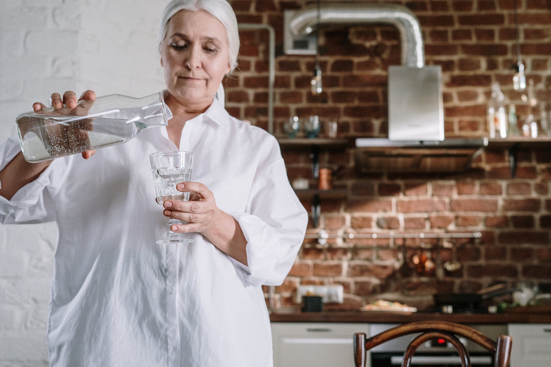 Mujer mayor sirviéndose un vaso de agua. | Foto: Pexels