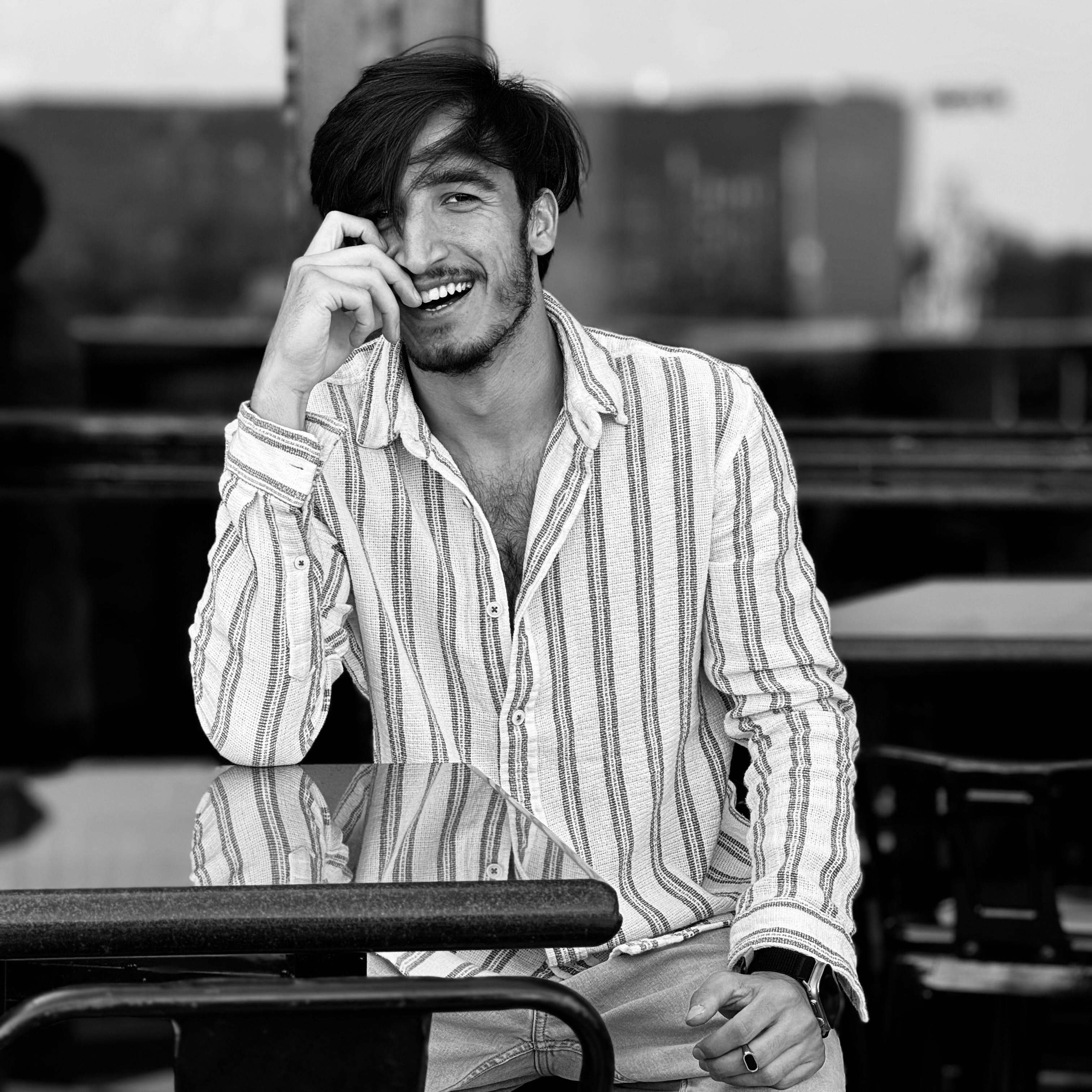 A man taking a seat at a cafe table, smiling | Source: Pexels