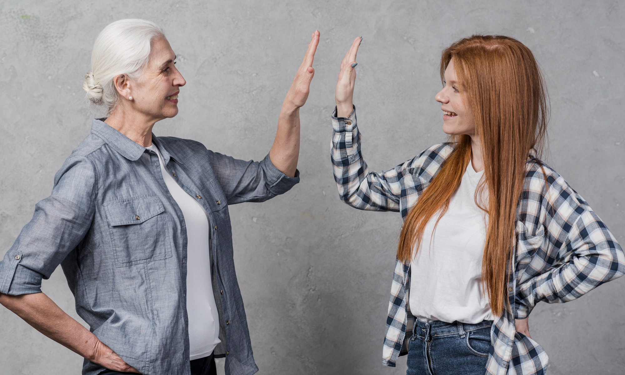An older woman and a young one sharing a high five | Source: Freepik