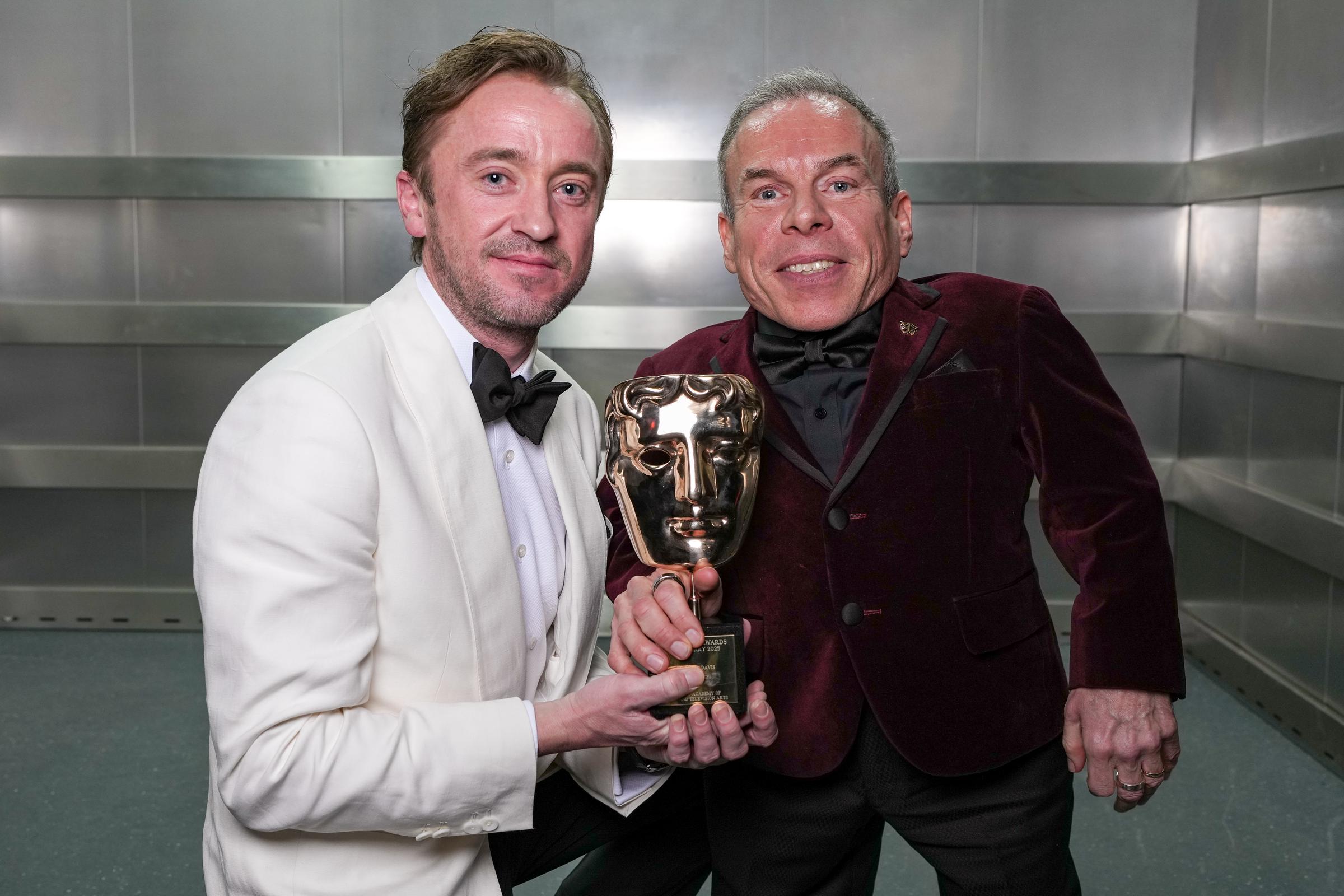 Tom Felton presents Warwick Davis with the Fellowship Award on February 16, 2025 | Source: Getty Images