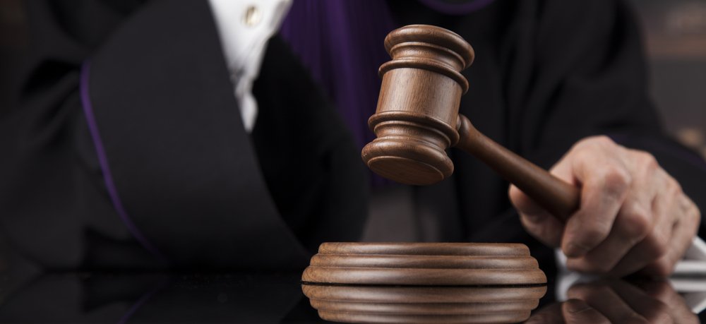Un juge qui utilise son marteau en bois au Tribunal. | Shutterstock