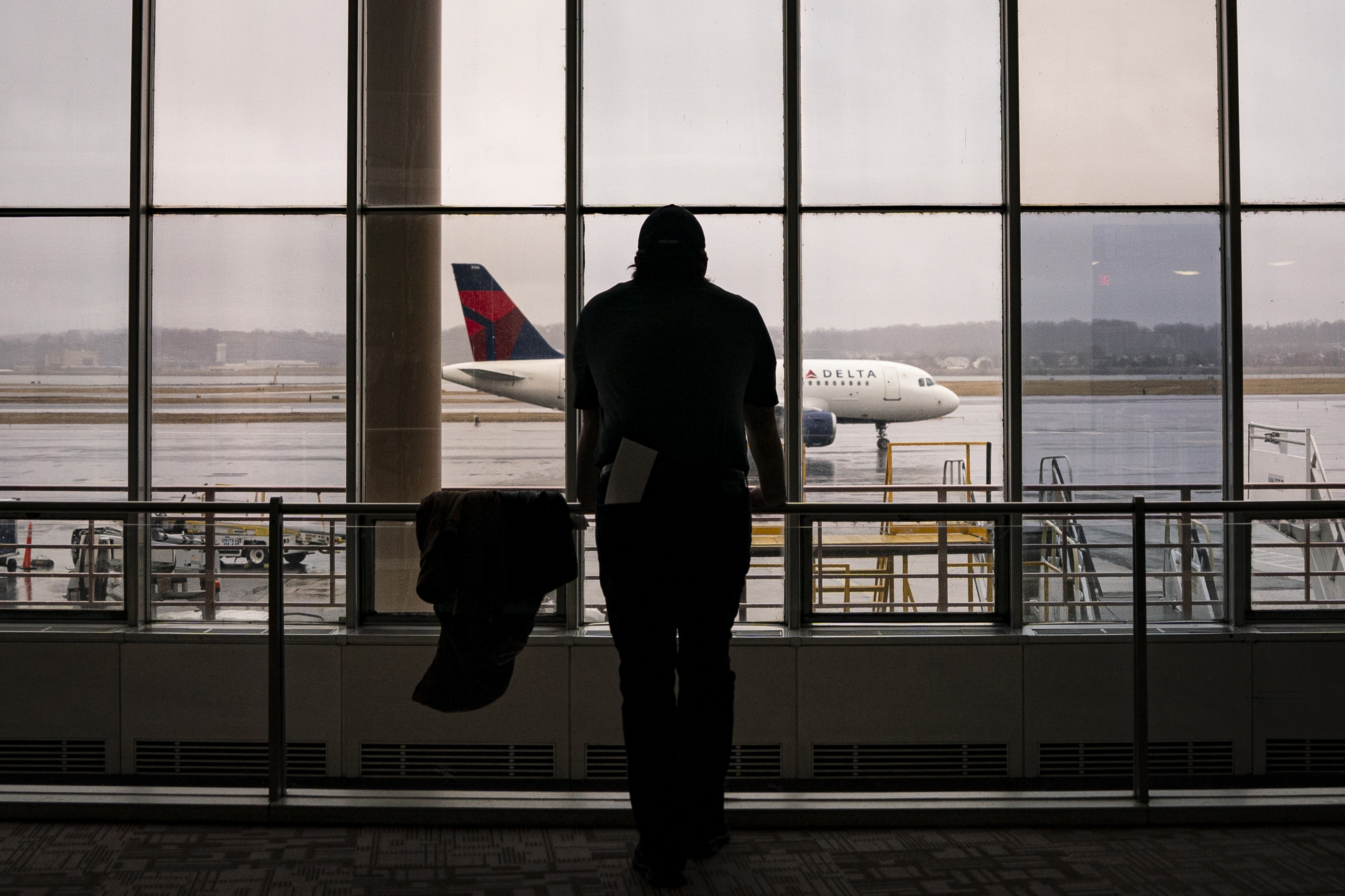 A worker looks out at a passing Delta Airlines plane on February 6, 2025, in Arlington, Virginia. | Source: Getty Images