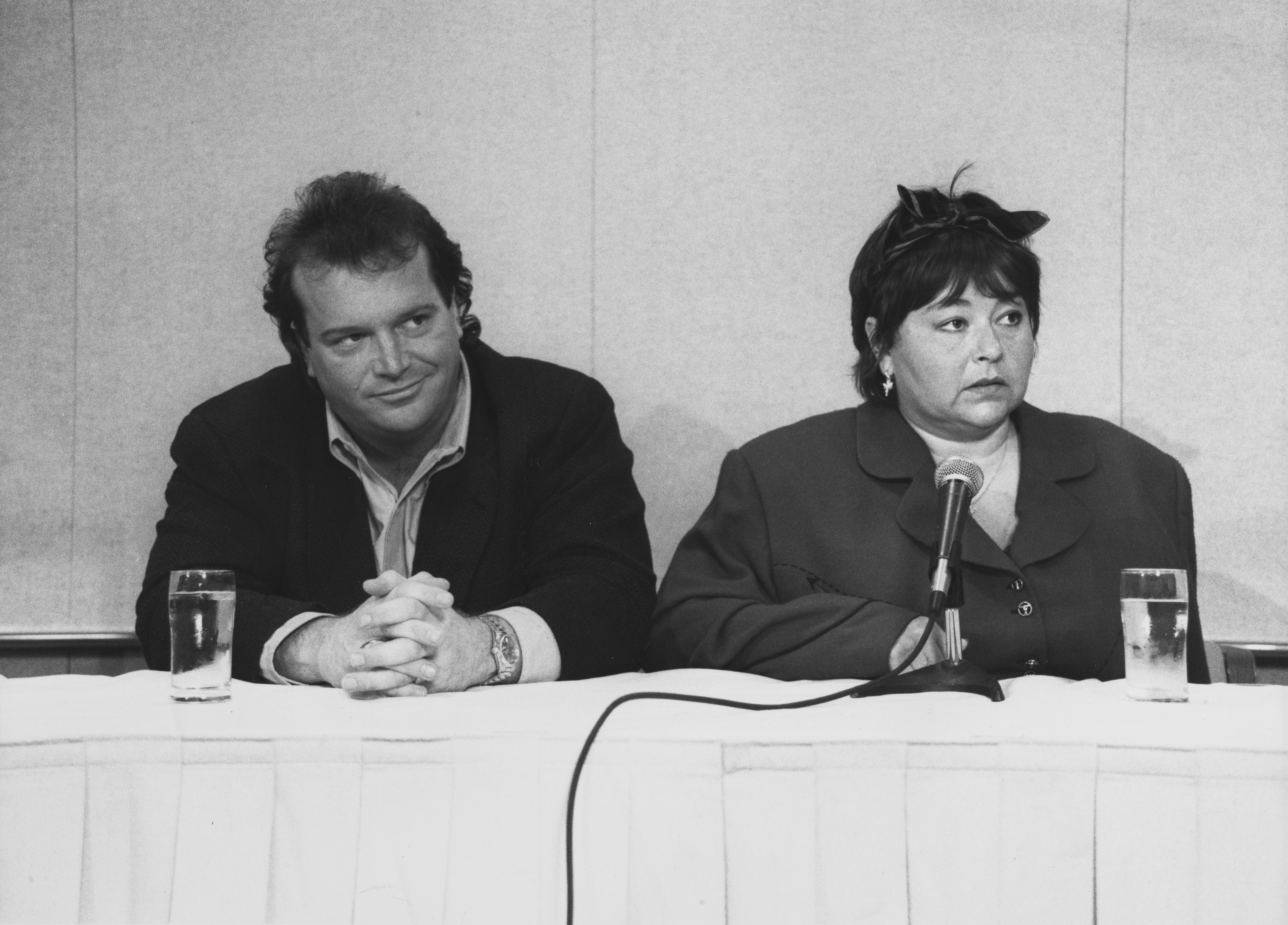 Comedian Roseanne Barr and her then-husband Tom Arnold held a press conference following her controversial performance of the national anthem. In this photo, they spoke to reporters in Los Angeles, California, in 1990. | Source: Getty Images