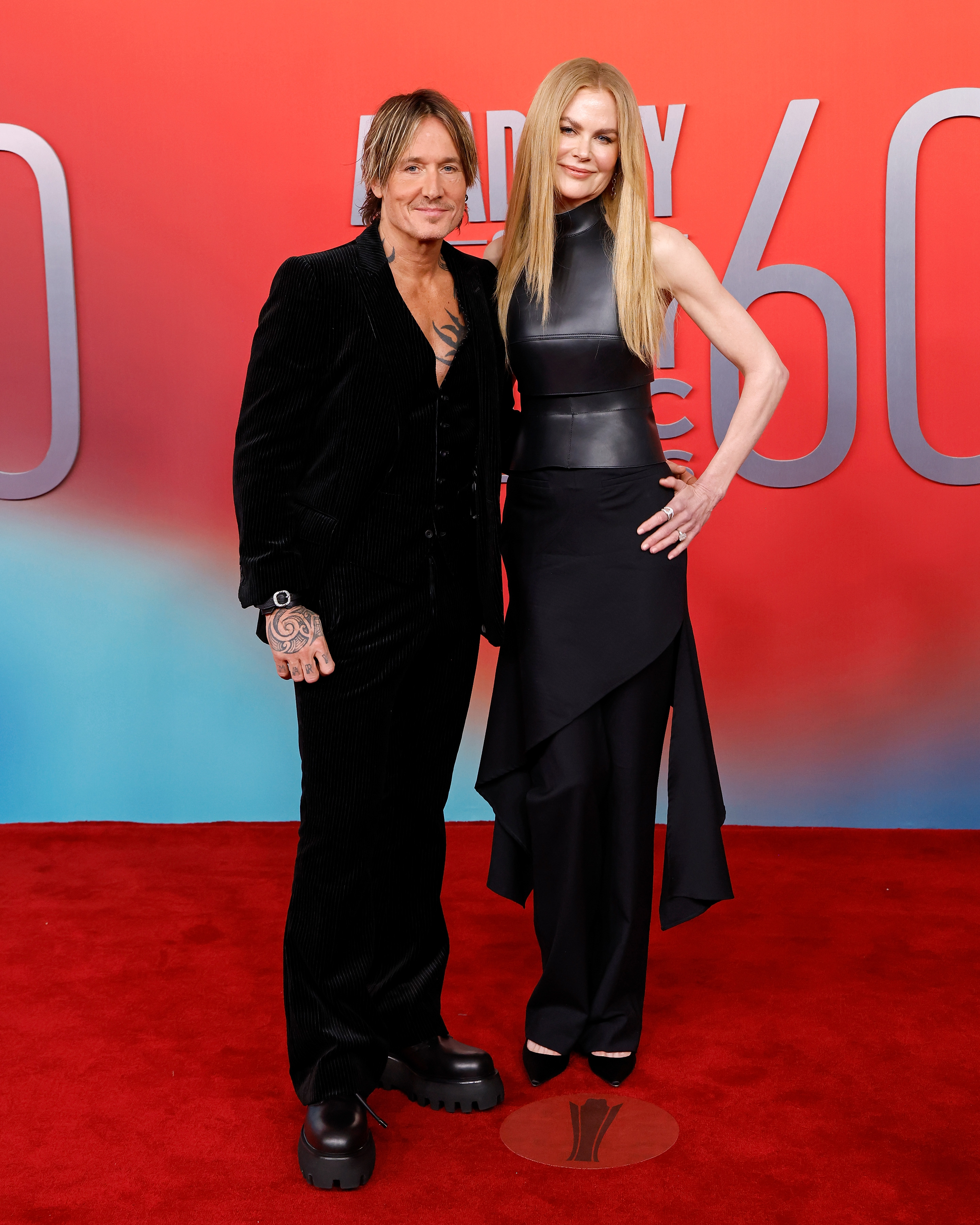 Keith Urban and Nicole Kidman attend the 2025 ACM Awards in Frisco, Texas. Urban pairs a black velvet suit with platform shoes, while Kidman stuns in a sleek black leather gown with asymmetrical detailing.