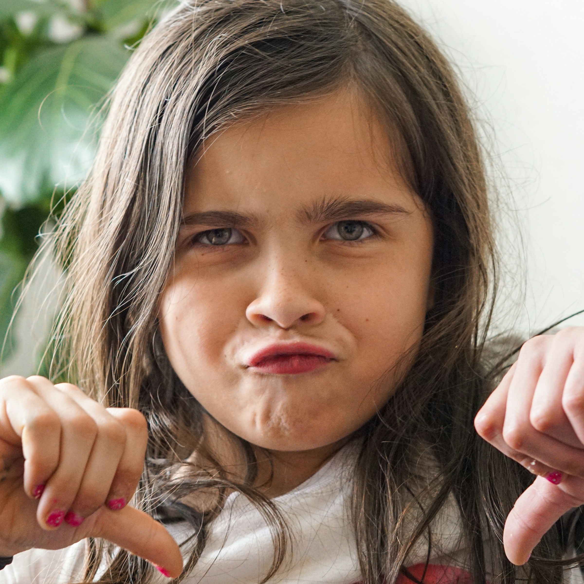 An upset child showing thumbs down | Source: Unsplash