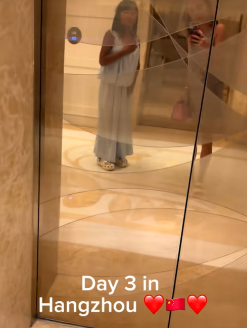 One of Amanda "Mandy" Karolkiewicz's daughters poses for a mirror selfie in a hotel lobby while wearing a light blue sleeveless dress and white clogs. | Source: TikTok/mandykarolk
